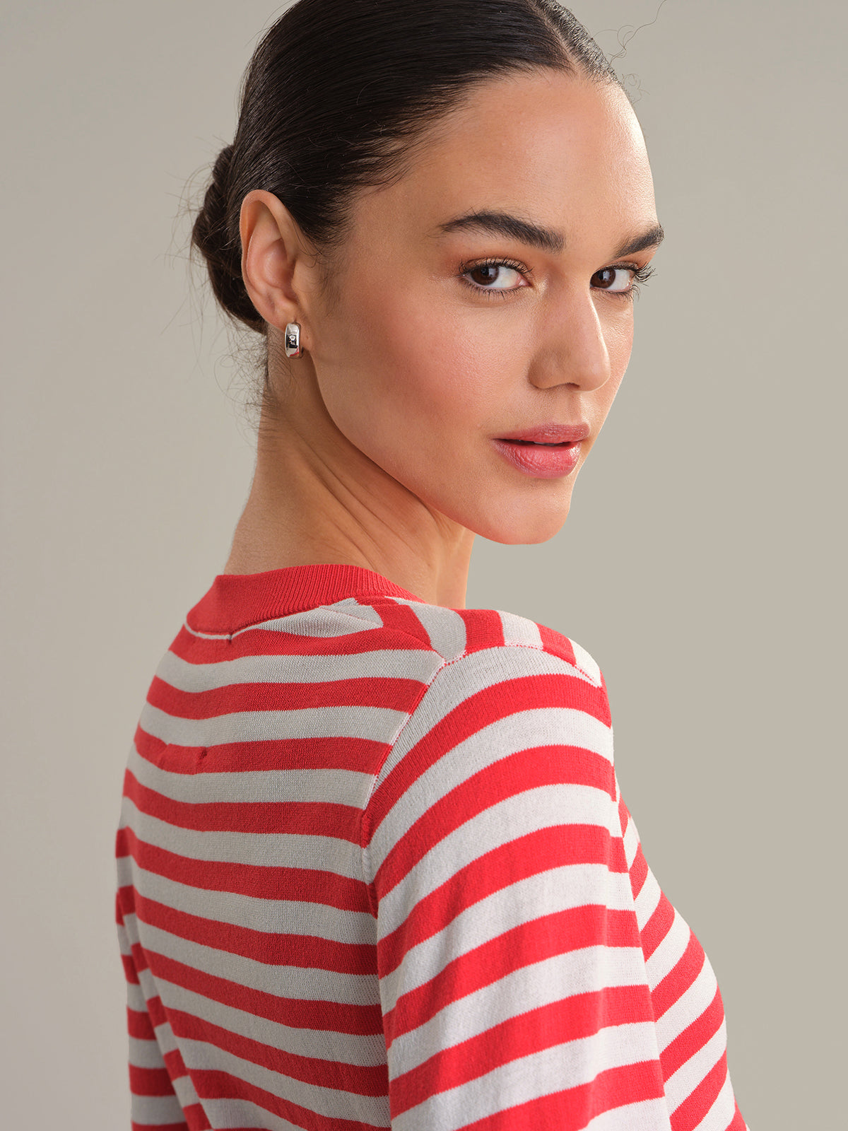 Woman wearing a red and white striped cardigan against a plain background