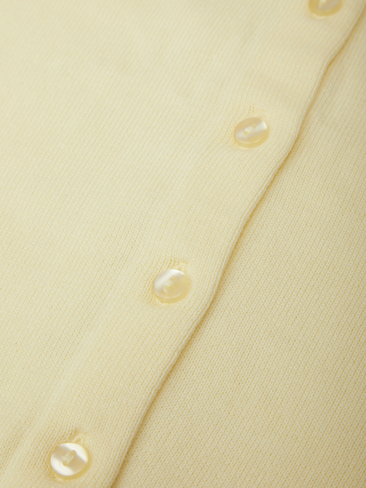 Close-up of a light yellow fabric with pearl-like buttons.