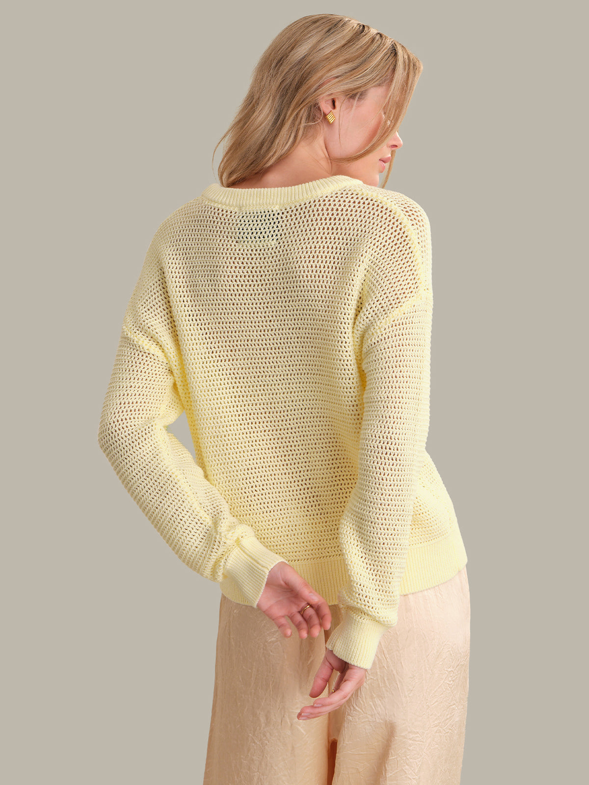 Woman wearing a light yellow sweater against a neutral background