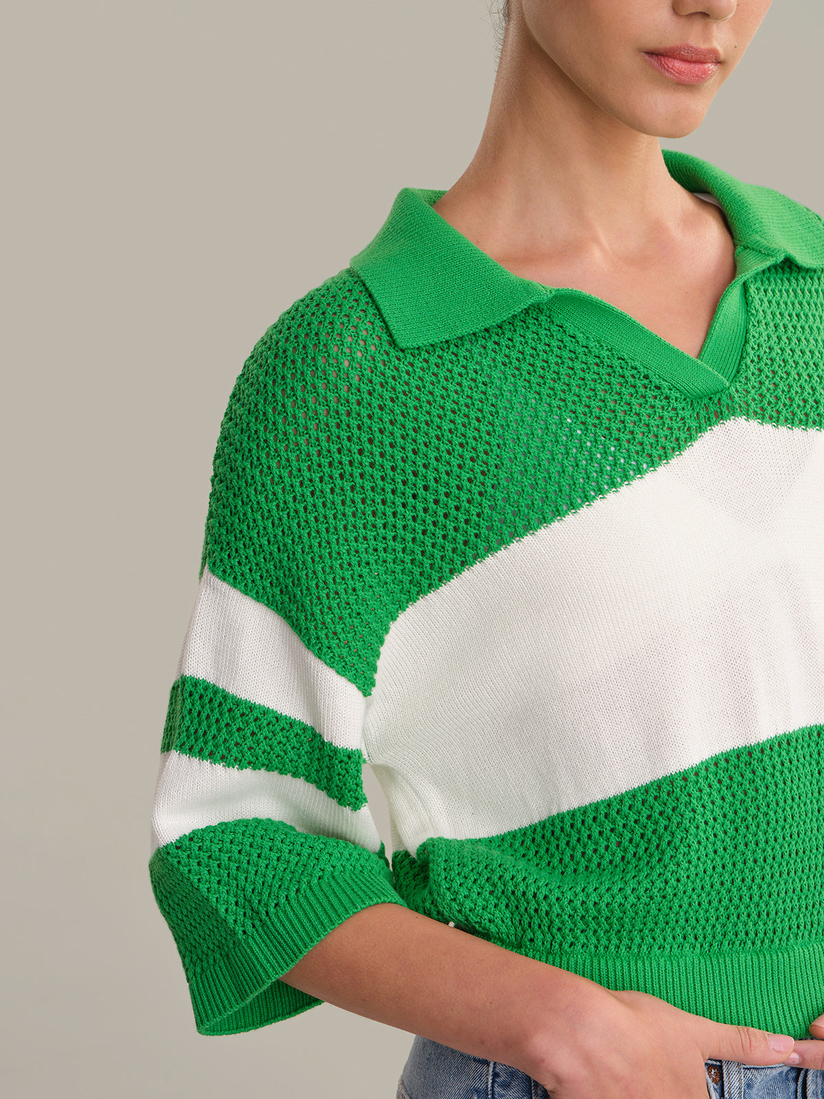 Green and white sweater worn by a person on a neutral background