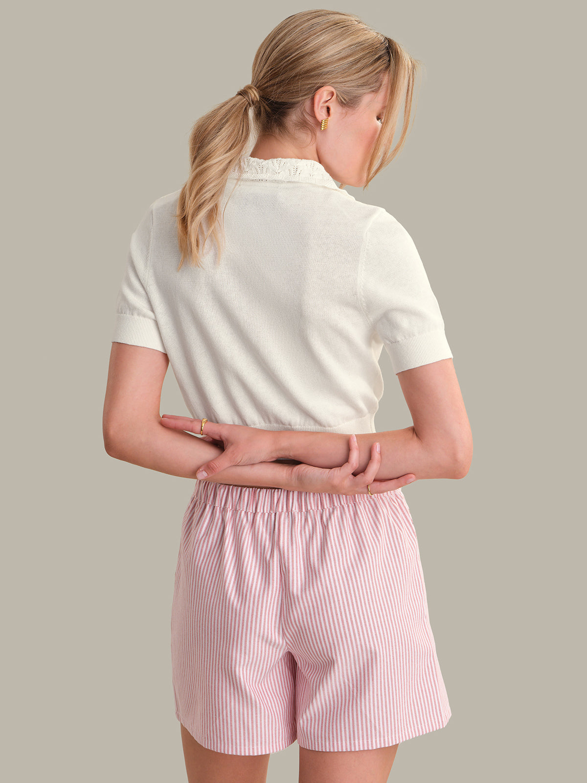 Person wearing a white polo shirt and pink shorts on a plain background