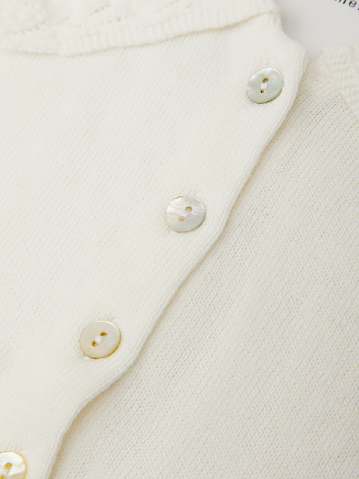 Close-up of a white textured garment with buttons on a light background