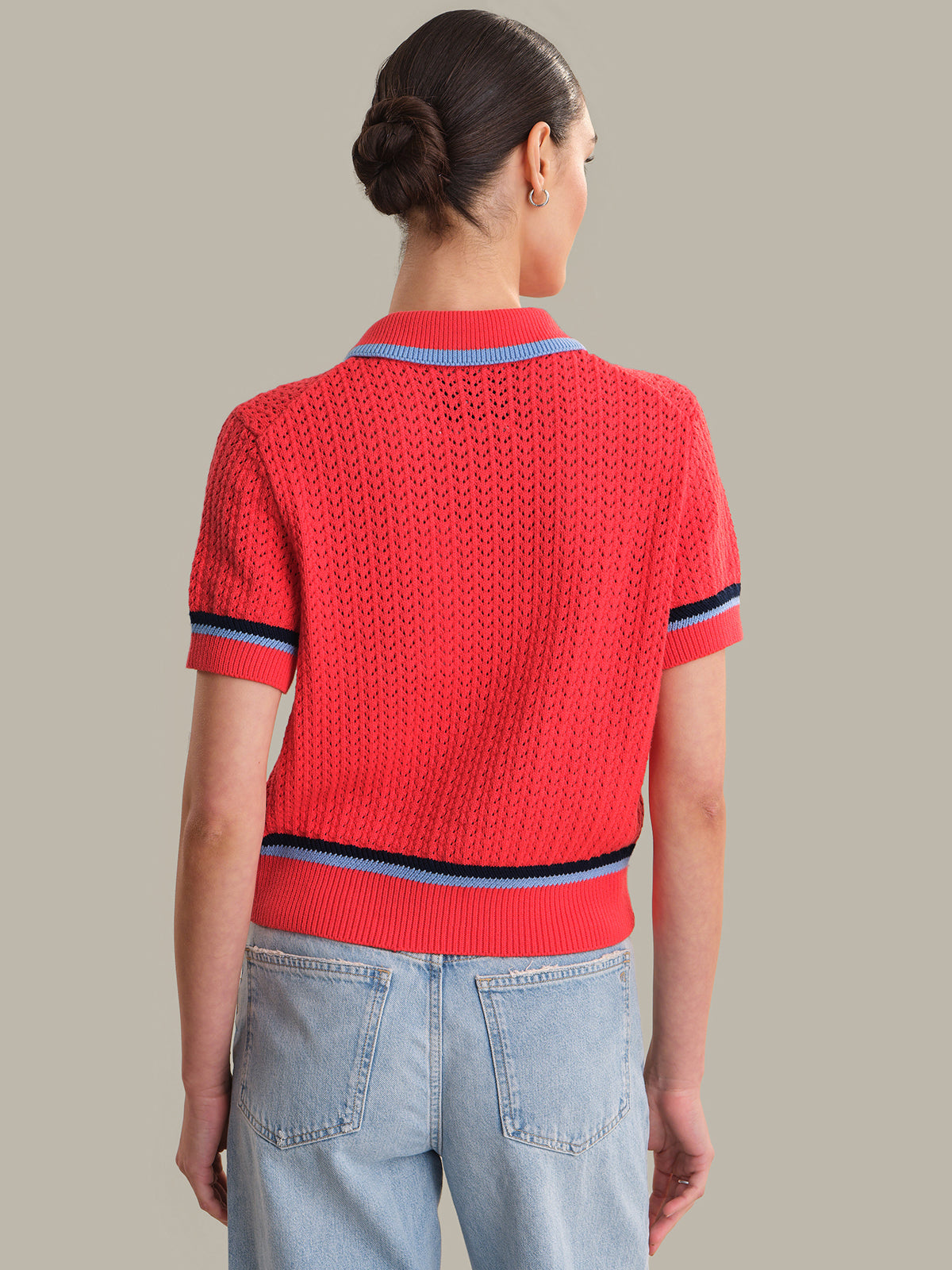 Person wearing a red knitted sweater with blue trim on a plain background