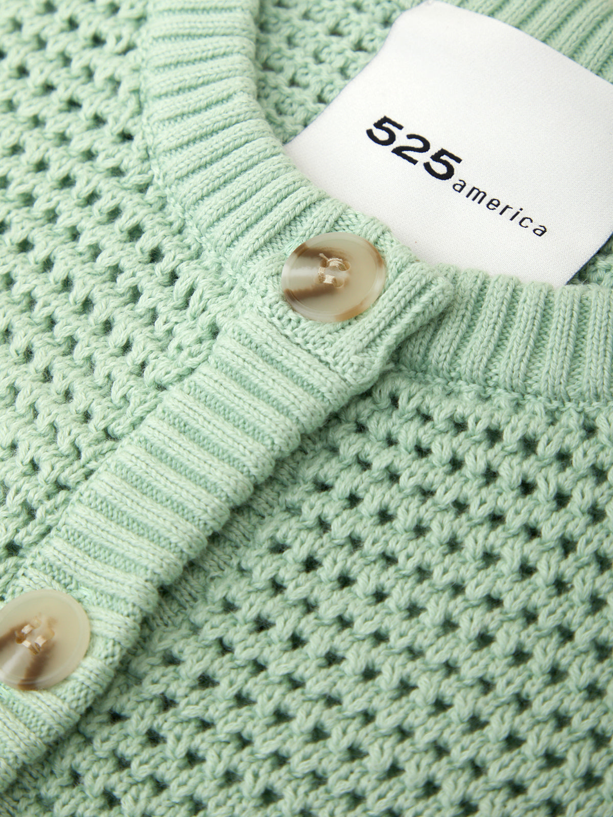 Close-up of a green textured garment with a tag displaying '525 america'.