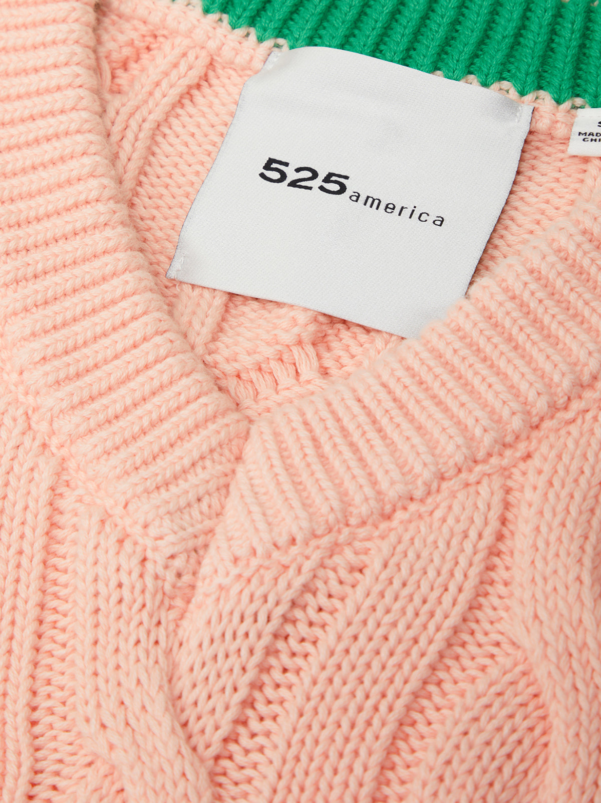 Close-up of a pink knitted sweater with a white label displaying '525 america'.