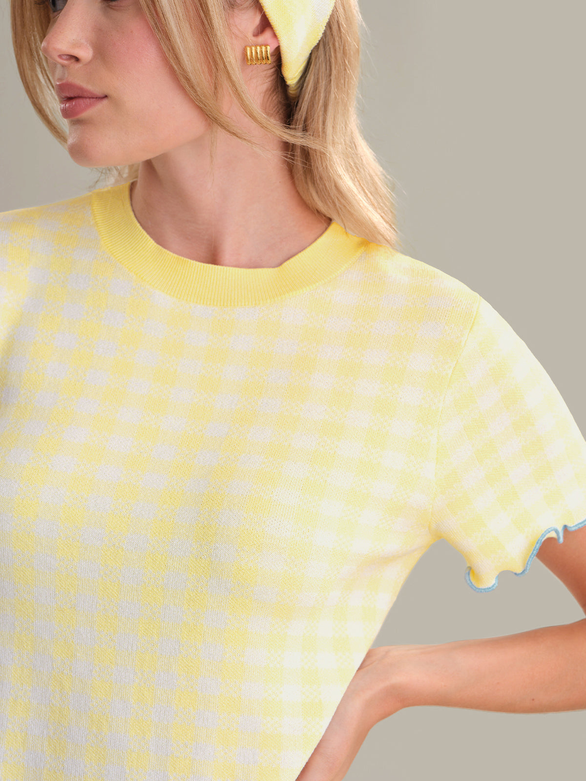 Woman wearing a yellow patterned top against a neutral background