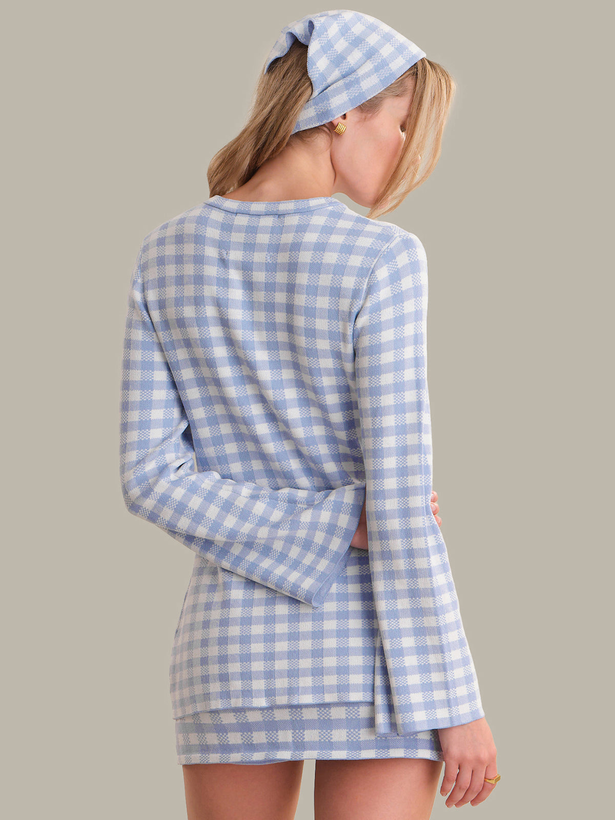 Woman wearing a blue and white checkered dress with a matching headscarf on a plain background