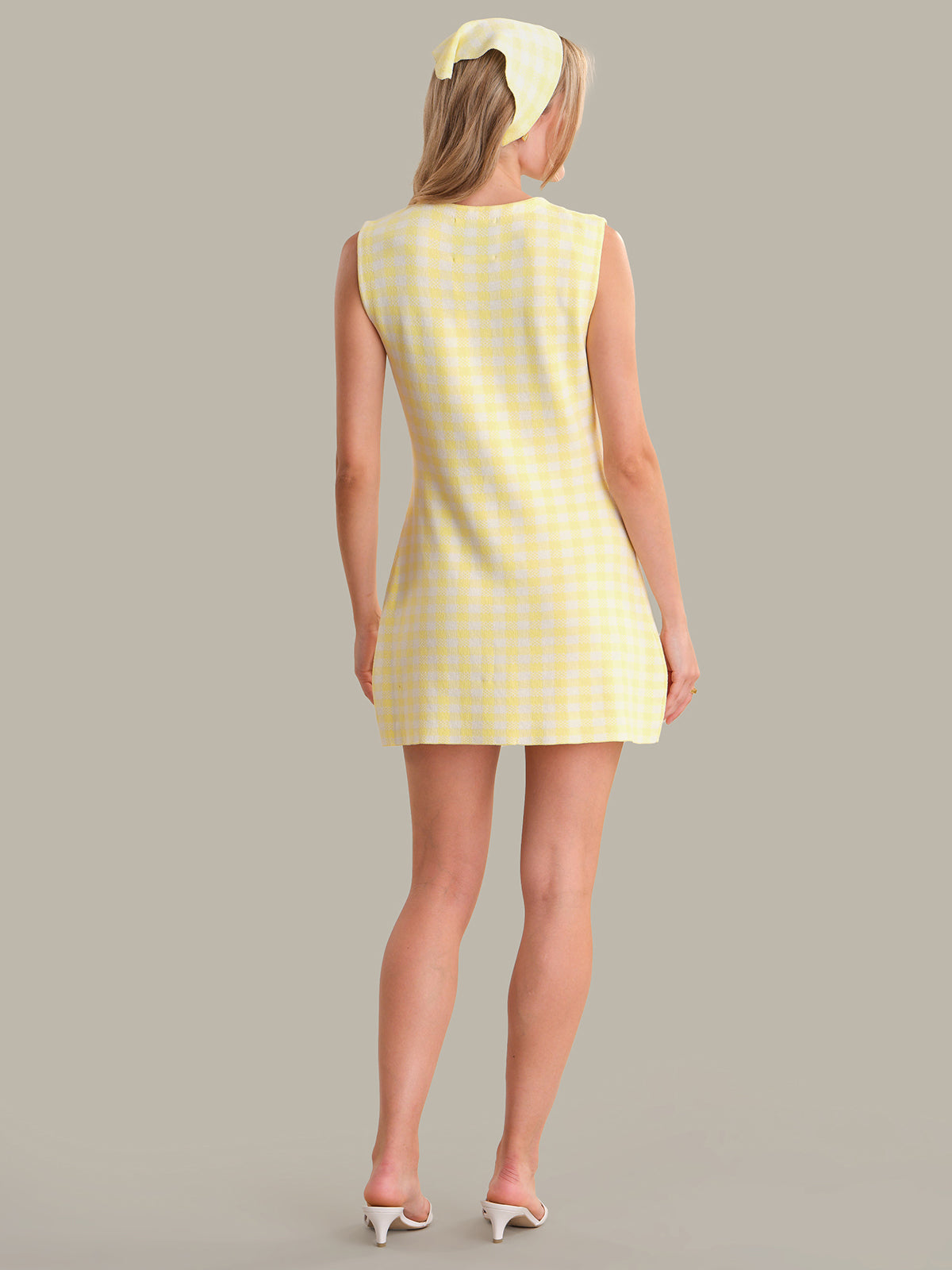 Woman wearing a yellow checkered dress against a gray background