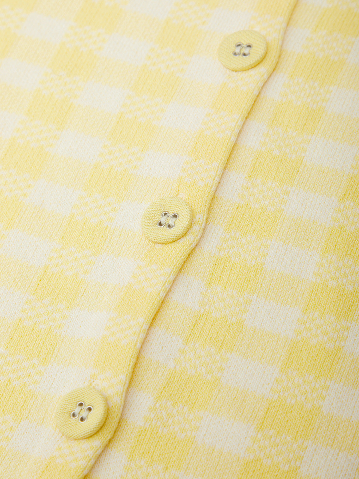 Close-up of a yellow and white checkered fabric with buttons.