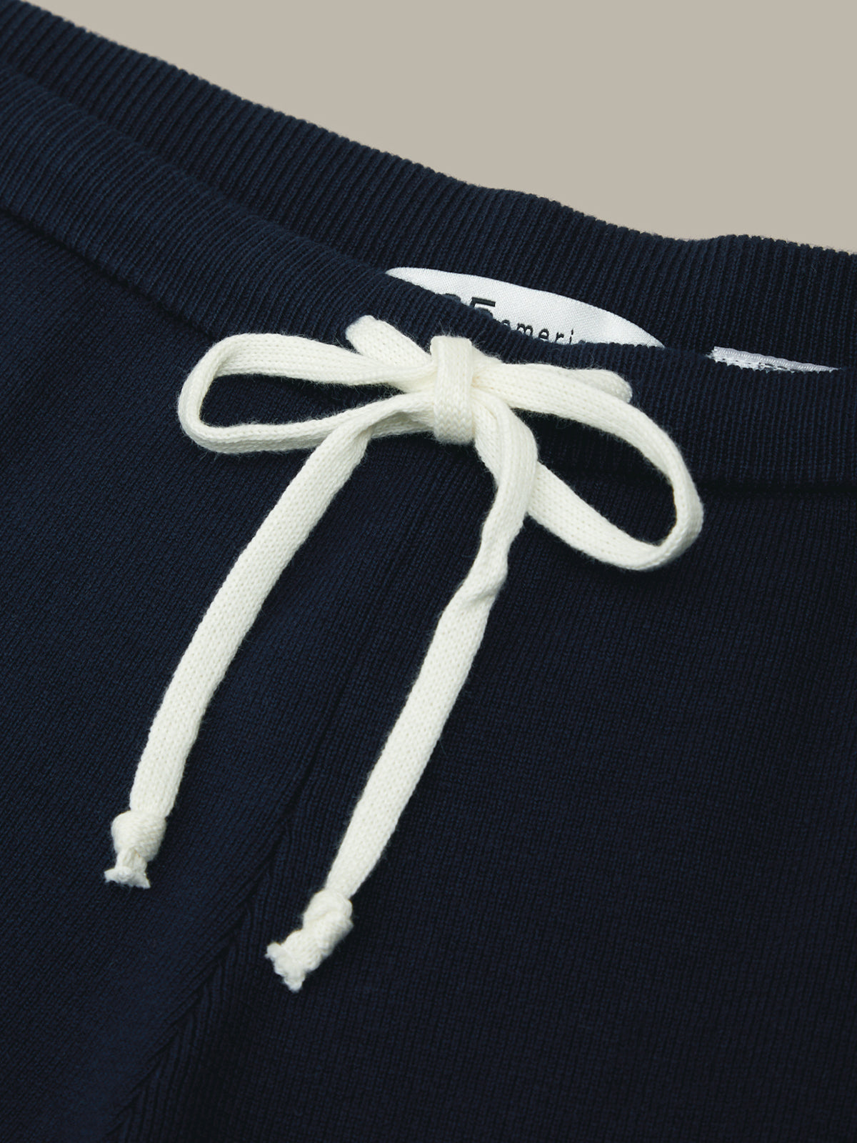 Navy blue sweatshirt with white drawstring on a beige background