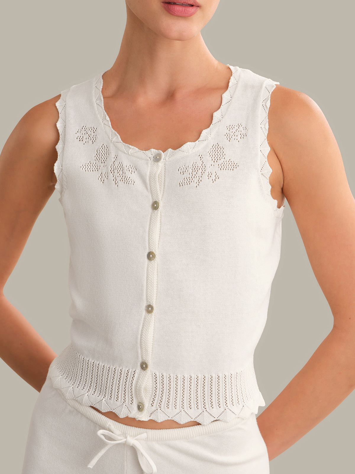 White sleeveless top with lace details on a neutral background