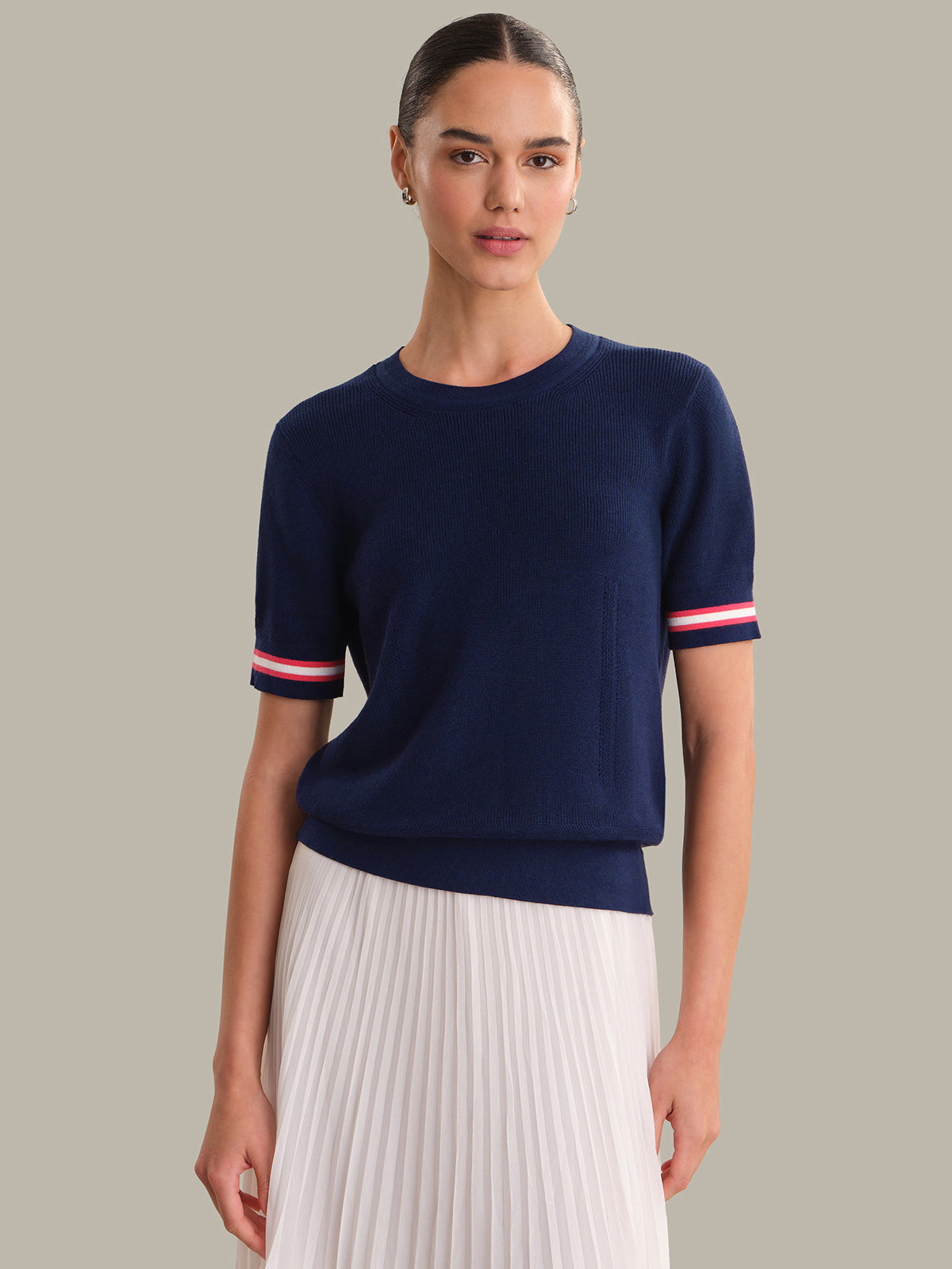 Woman wearing a navy sweater with red and white stripes on a neutral background