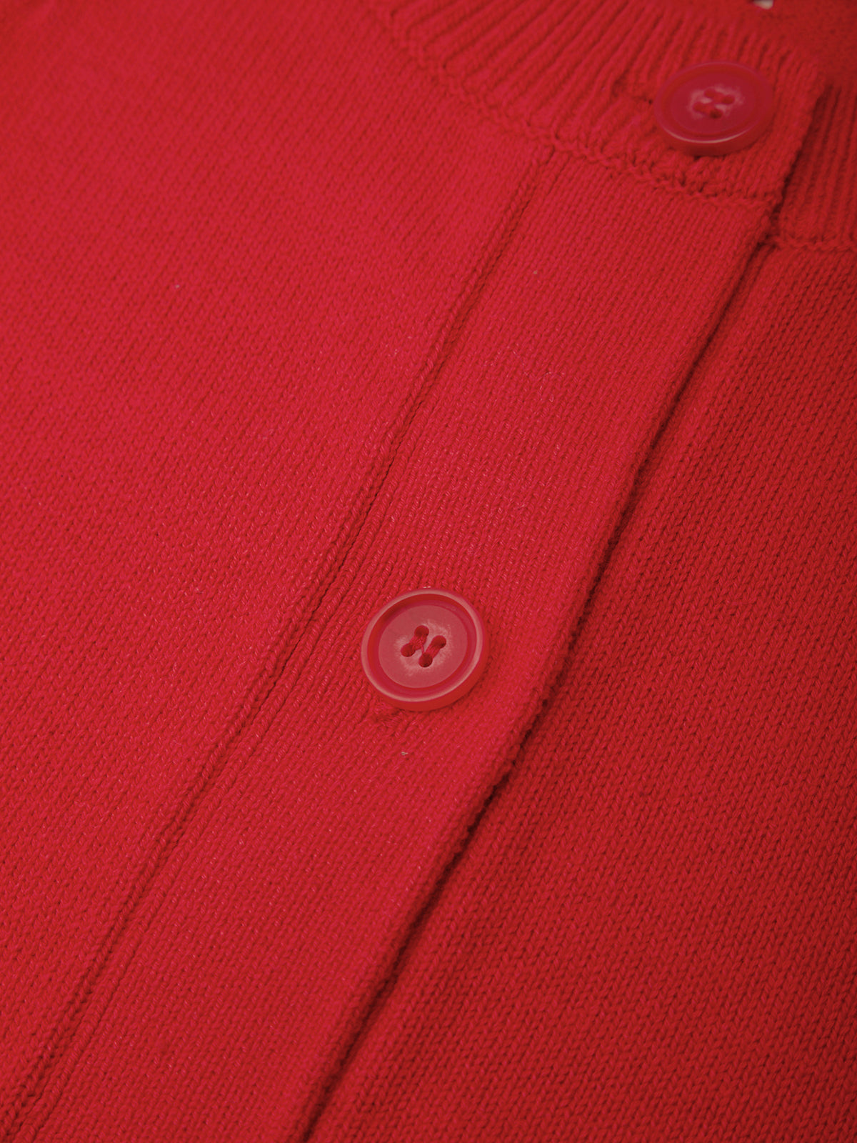 Close-up of a red cardigan with buttons on a matching fabric background