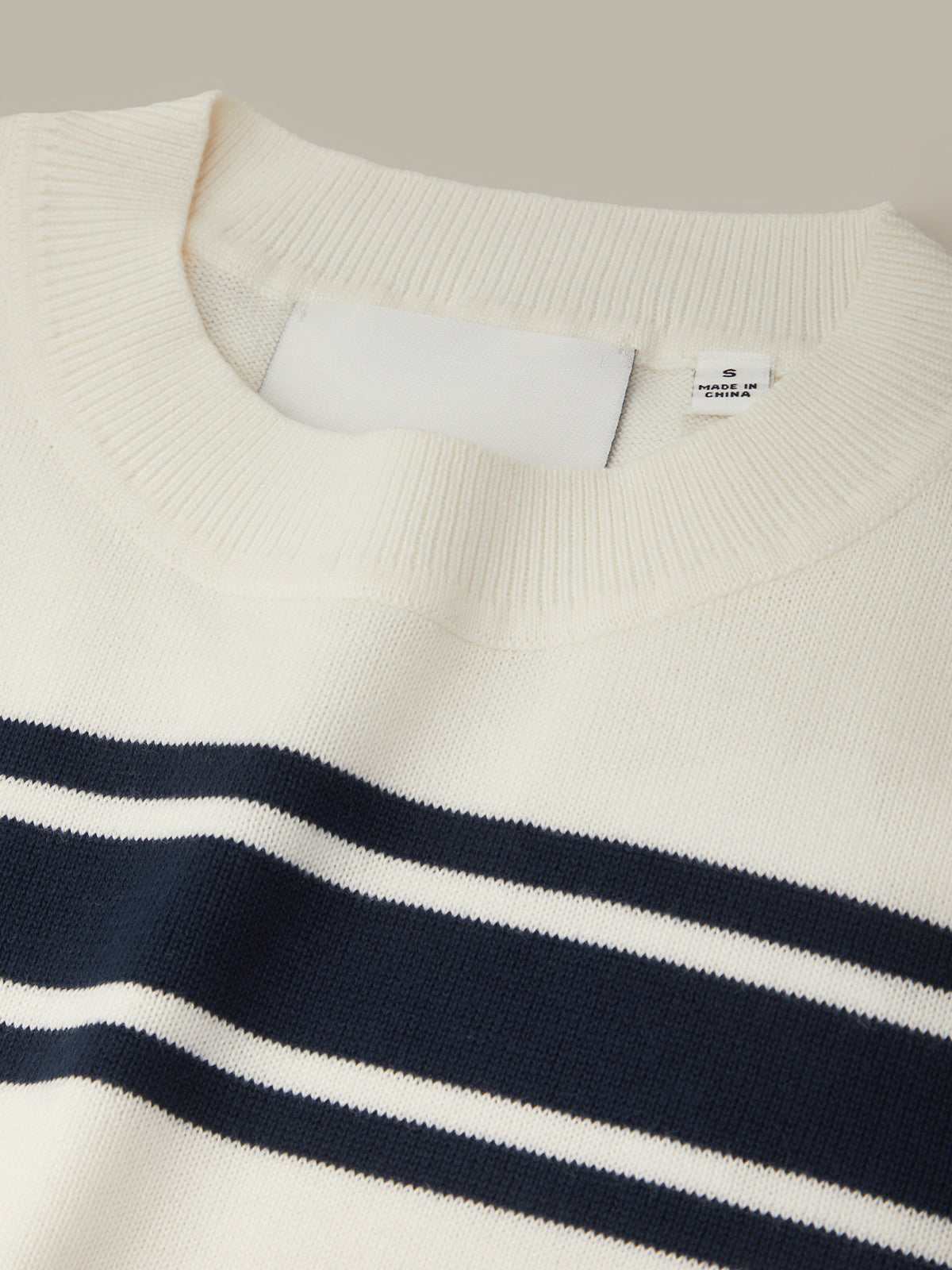 Close-up of a sweater with navy and white stripes on a neutral background