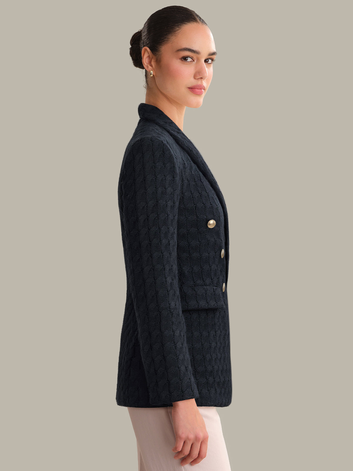 Woman wearing a dark quilted jacket on a plain background