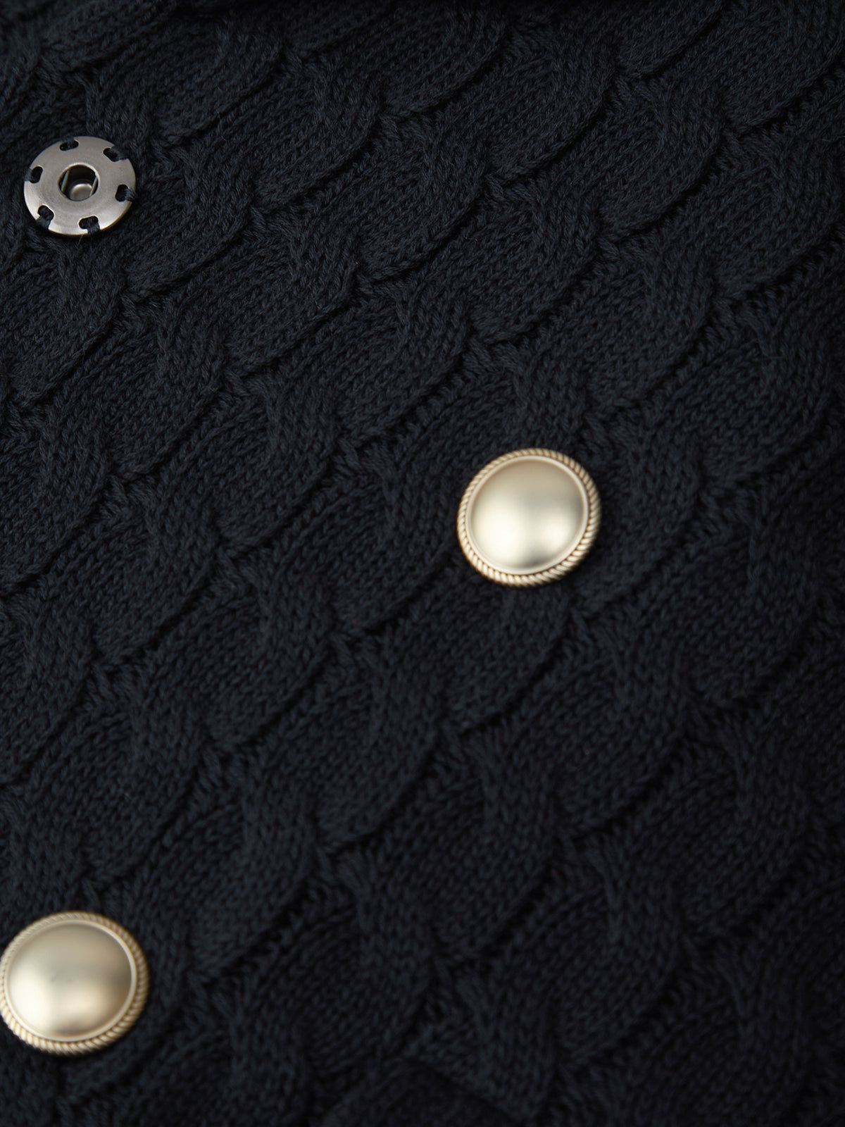 Close-up of a dark textured fabric with pearl-like buttons.