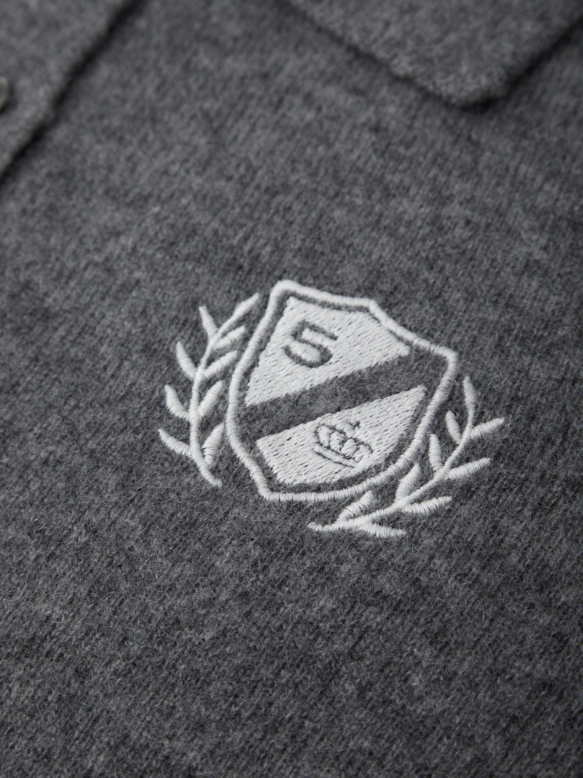 Embroidered logo on a dark gray fabric background