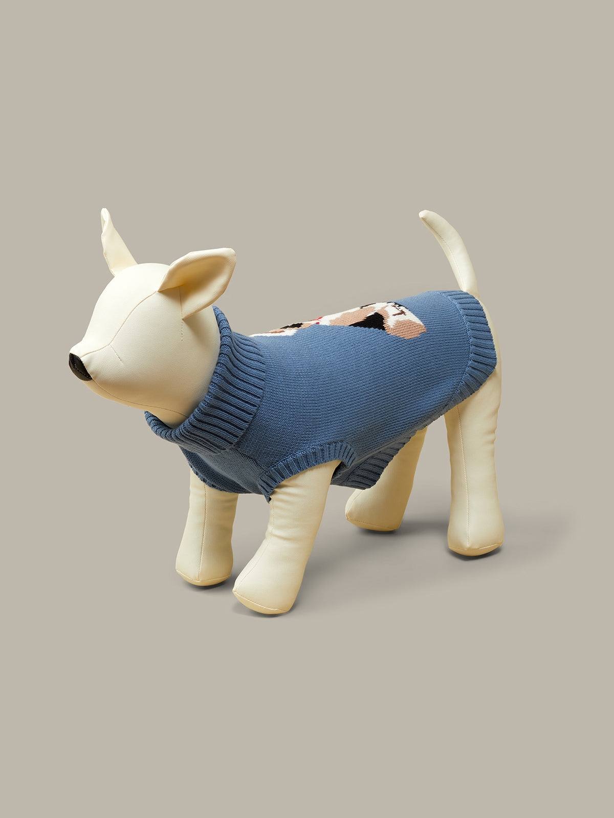 Dog figurine wearing a blue sweater on a neutral background