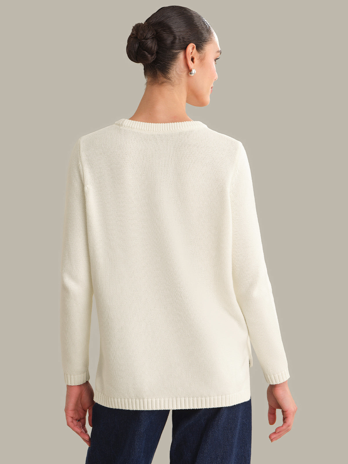 Woman wearing a cream sweater against a gray background