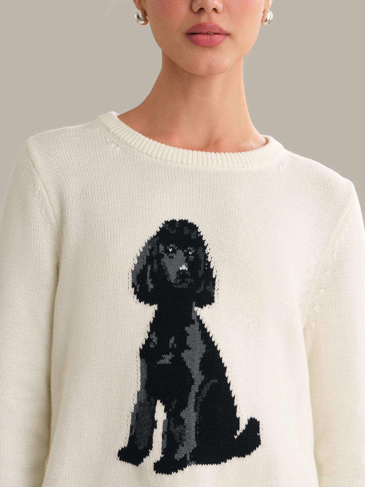 White sweater with a black dog design worn by a person against a neutral background