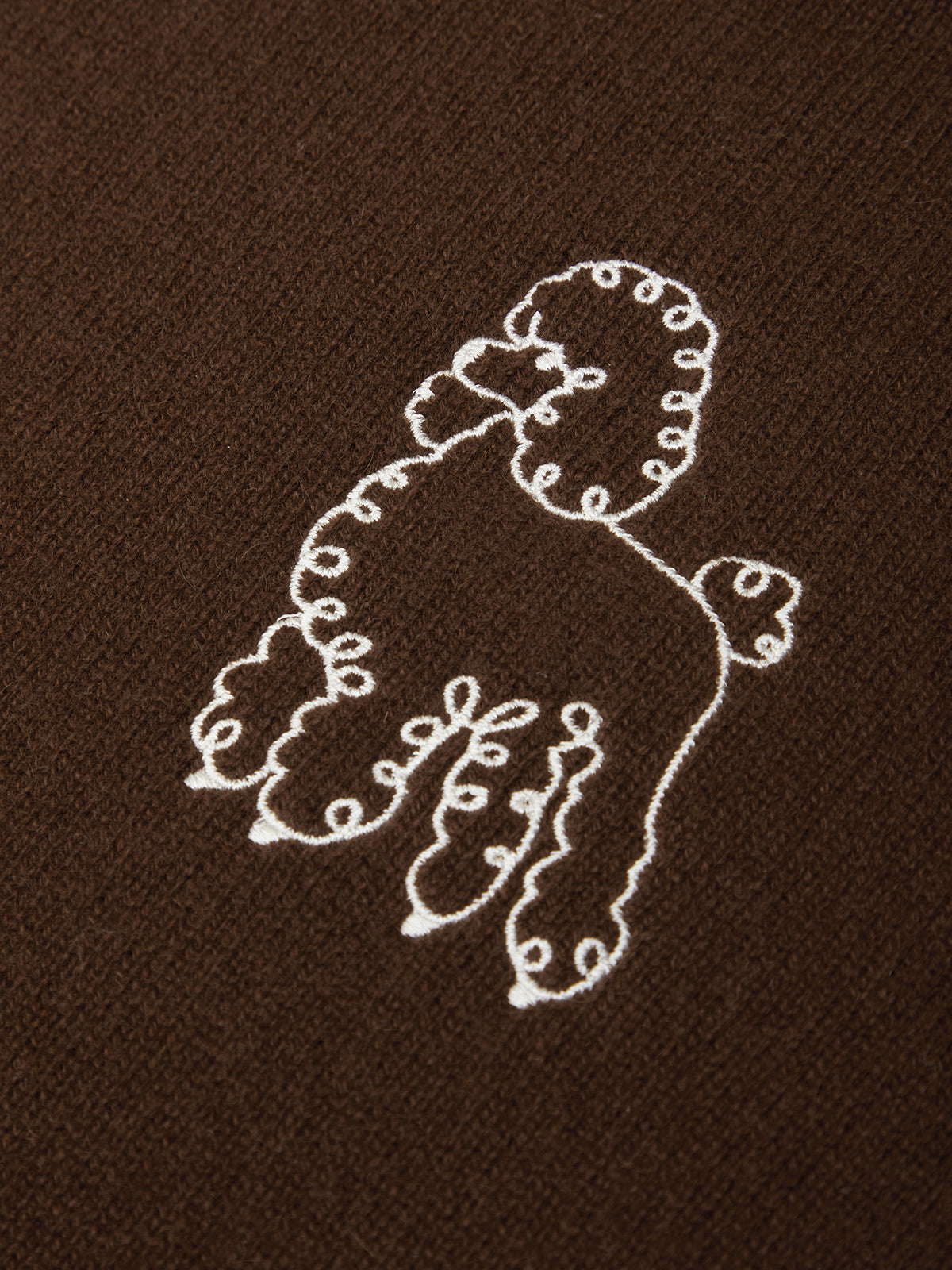 Embroidered design of a poodle on brown fabric