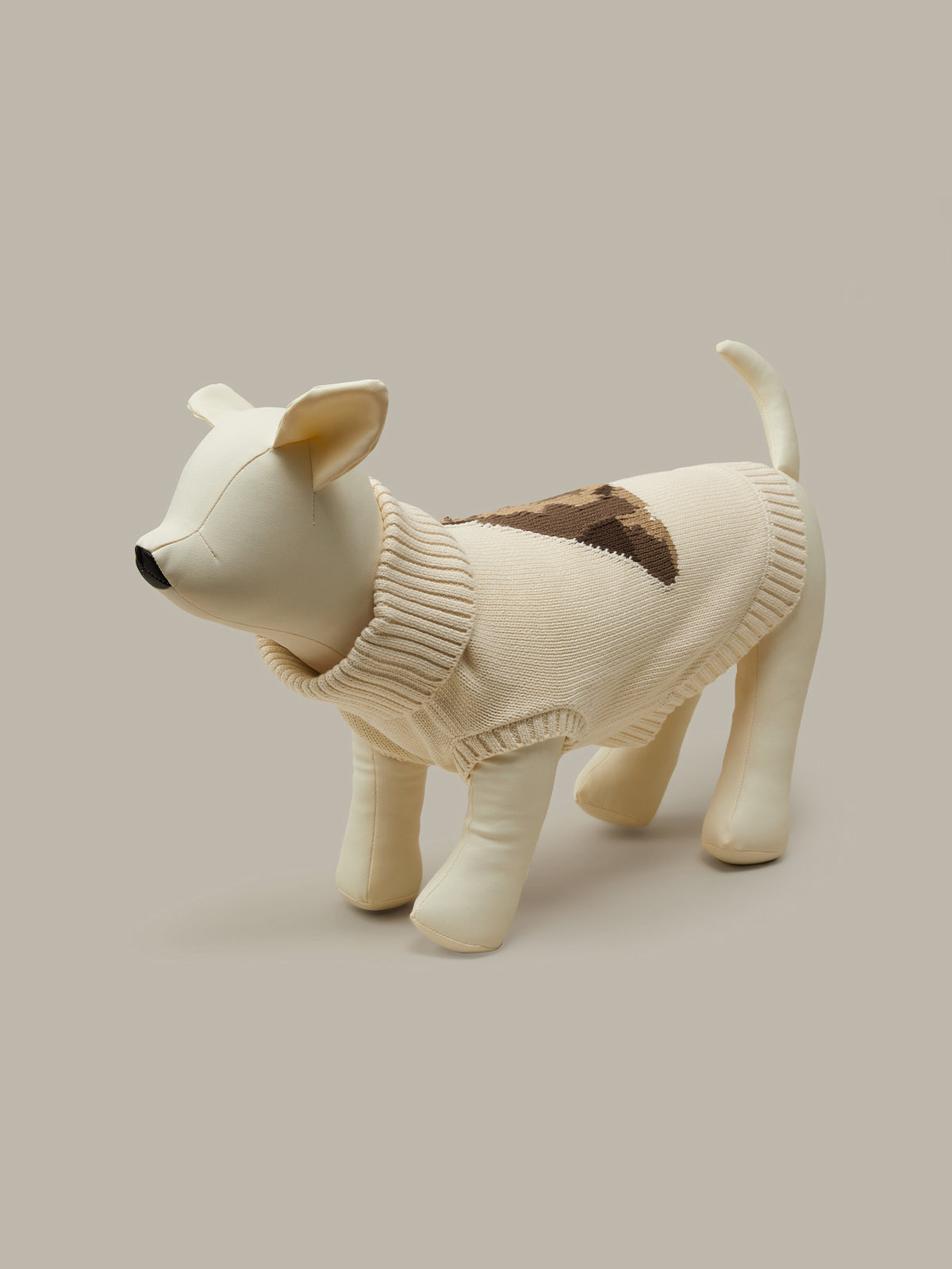 Dog-shaped plush toy wearing a sweater on a beige background