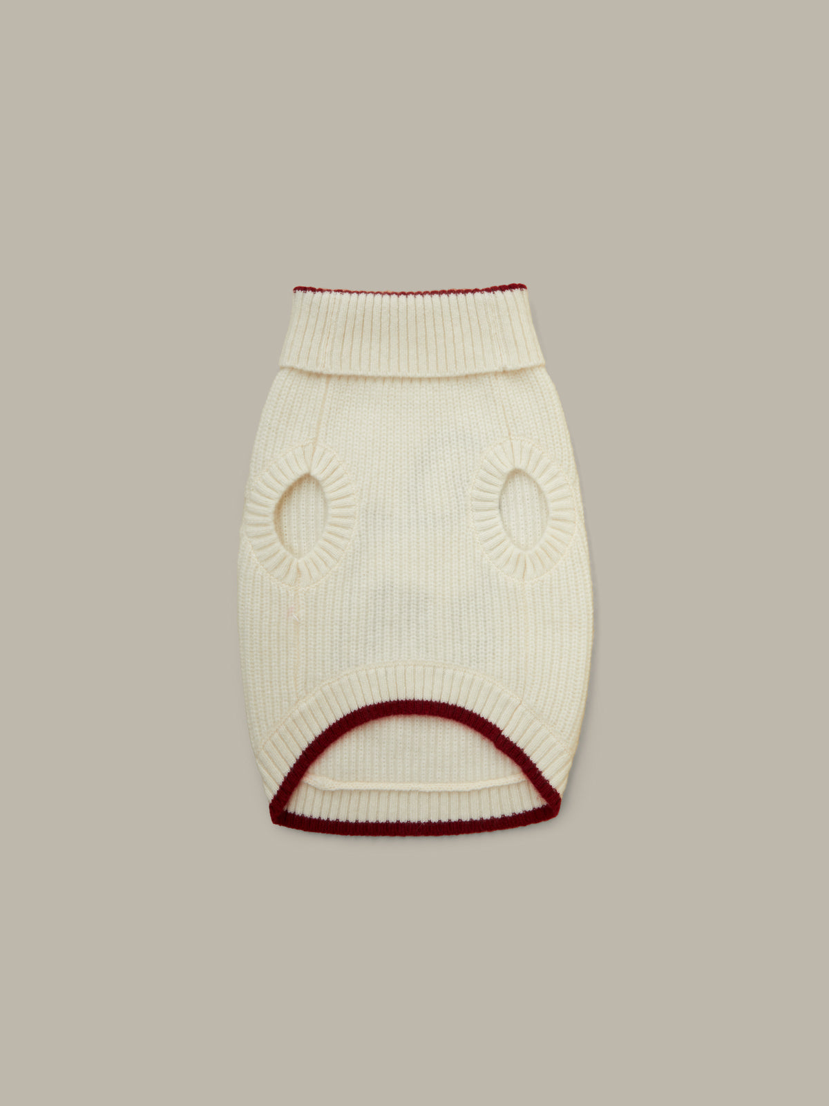 White knit dog sweater with red trim on a beige background