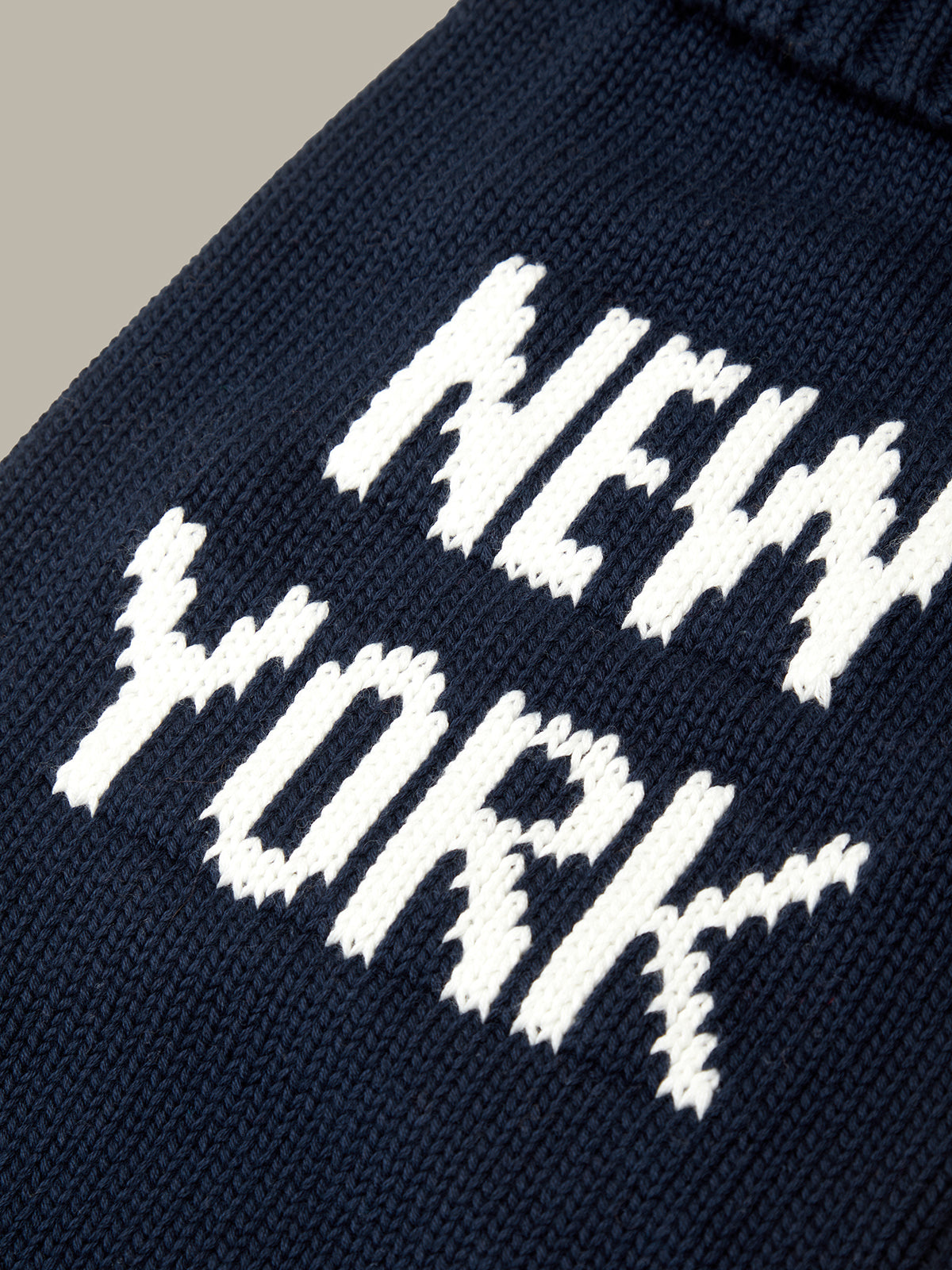 Navy blue knit sweater with 'New York' text in white on a neutral background