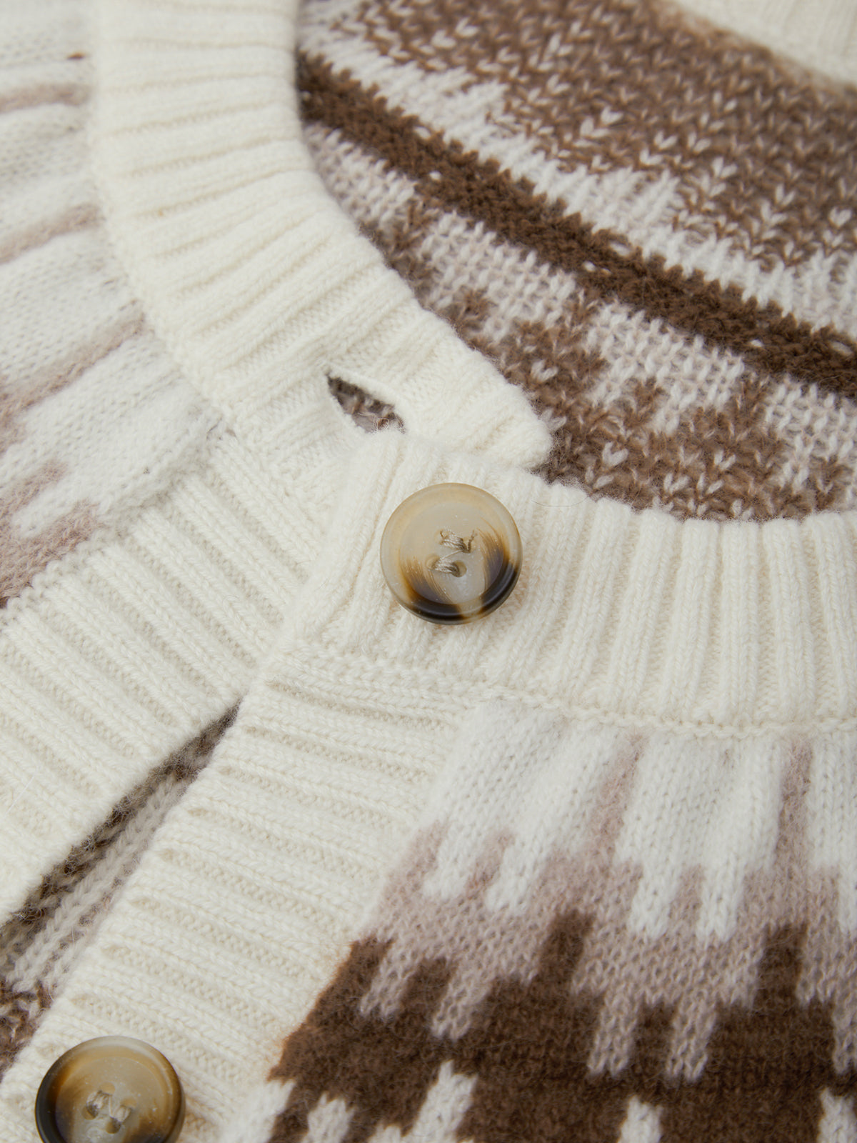 Close-up of a knitted sweater with buttons and brown and white pattern