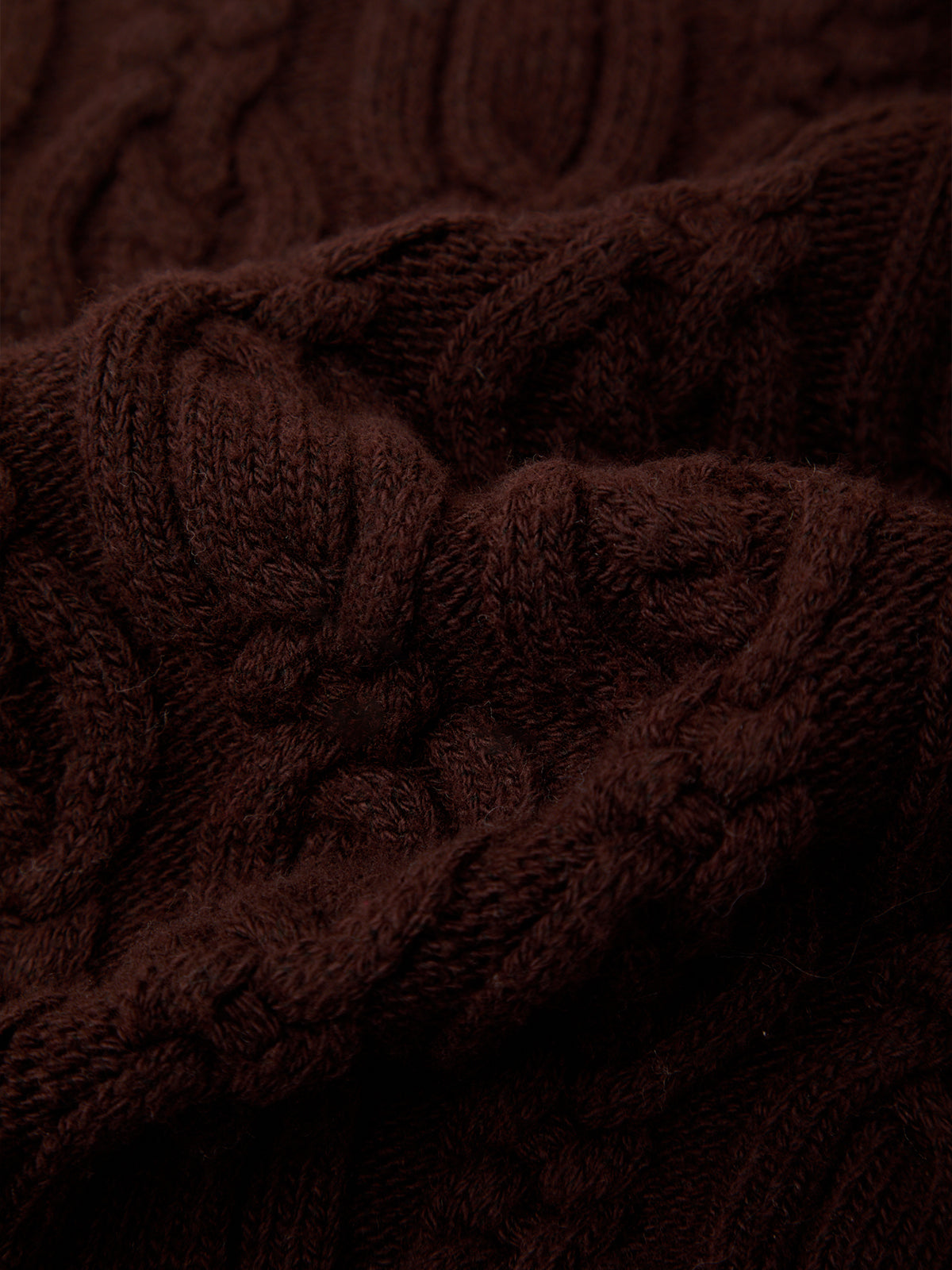 A close-up of a dark brown cable-knit fabric with a rich, textured weave.