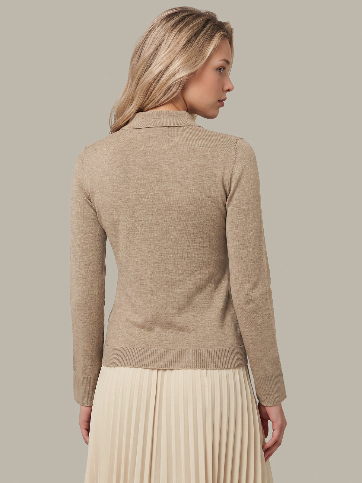 A woman shown from the back wearing a beige knit cardigan with a collar and a cream pleated skirt, set against a solid light gray studio background.