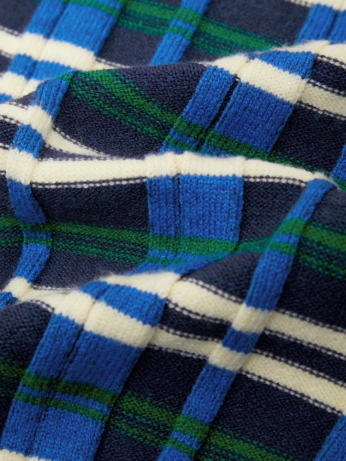 A close-up of a ribbed knit fabric with a plaid pattern in blue, navy, green, and white.