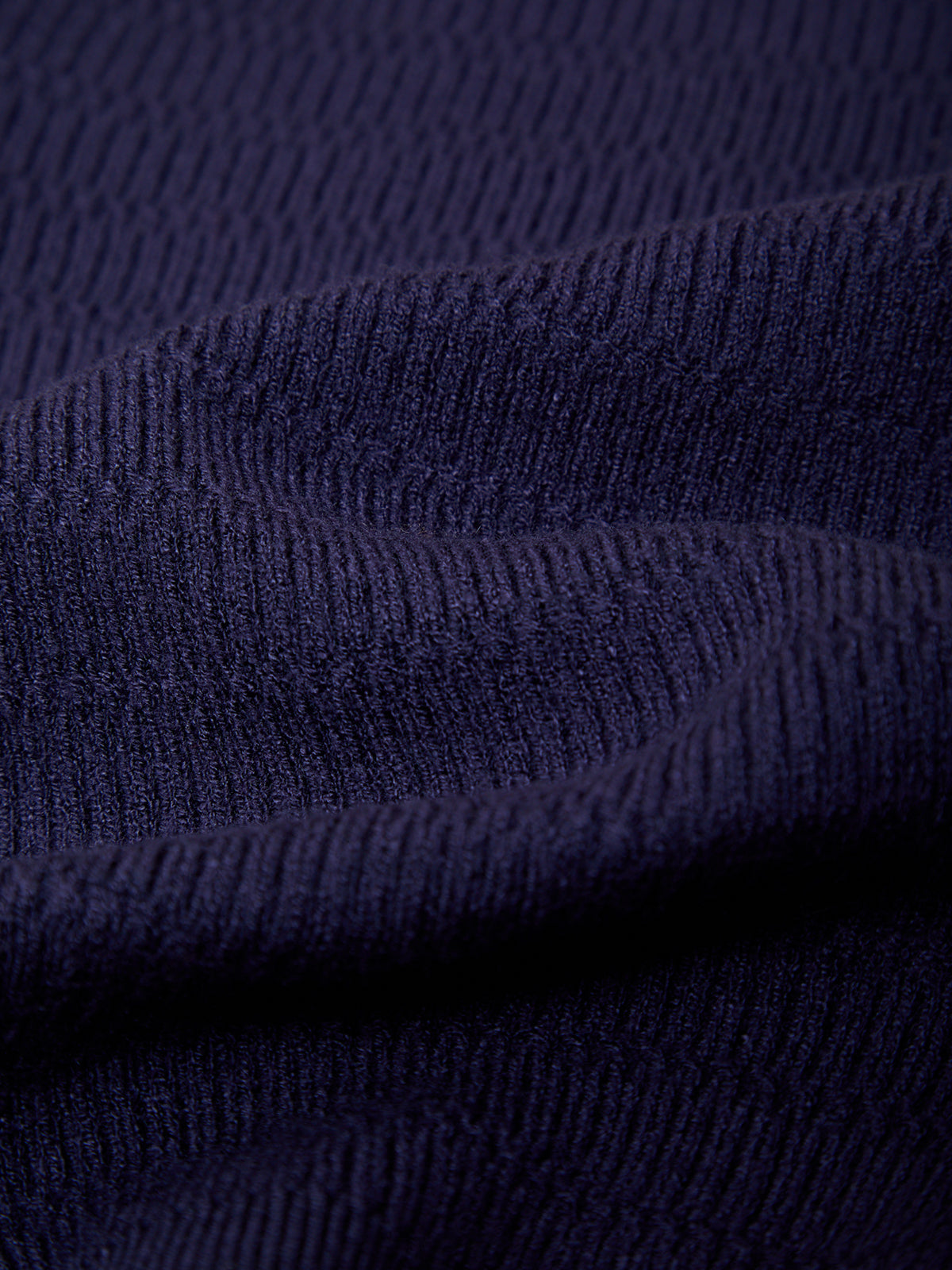 Close-up of a dark navy ribbed knit fabric texture with soft folds.