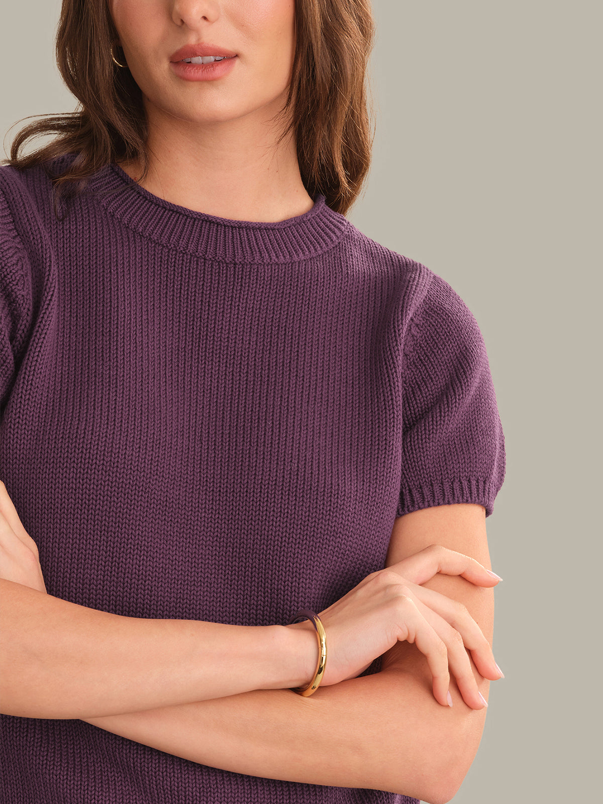 Woman wearing a purple sweater with a neutral background