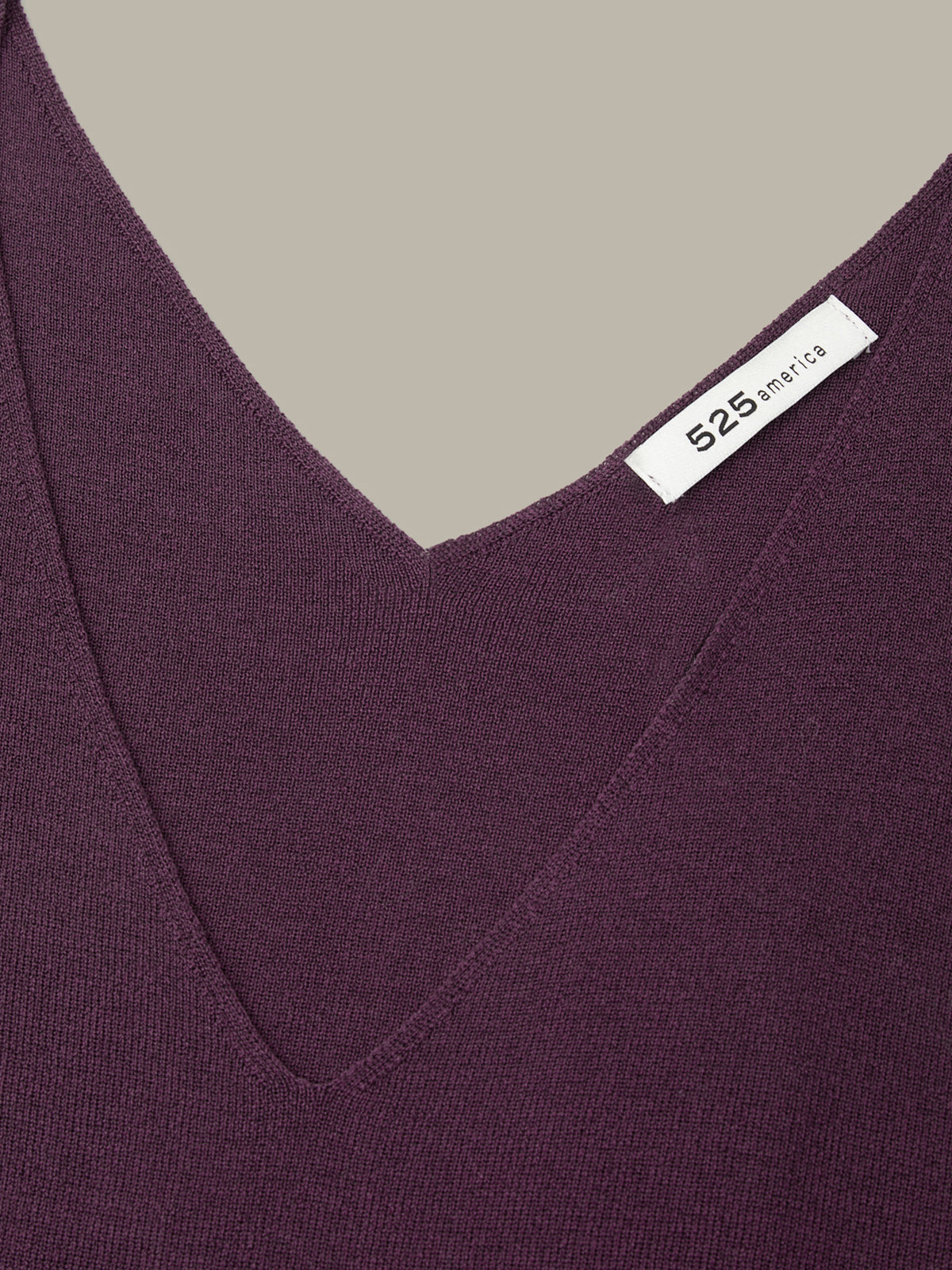 Close-up of a purple garment with a brand label on a neutral background