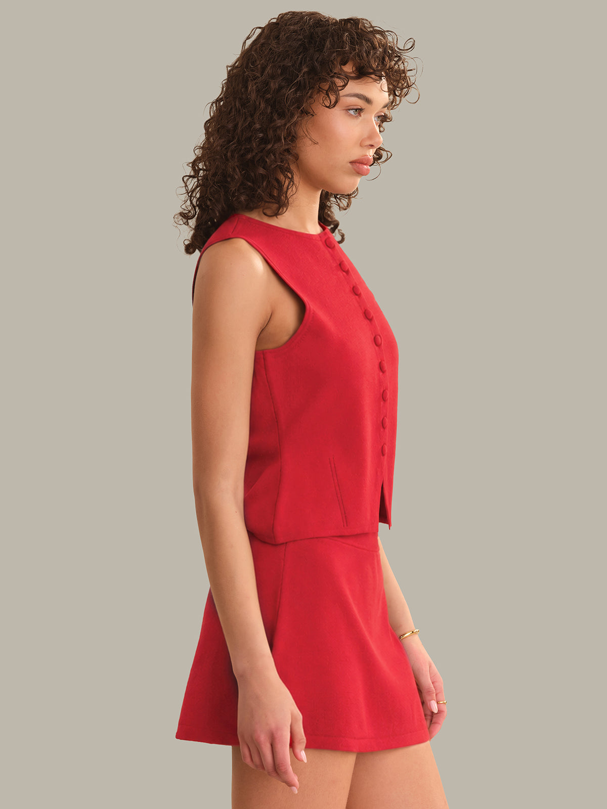 Woman wearing a red sleeveless top and skirt set against a gray background