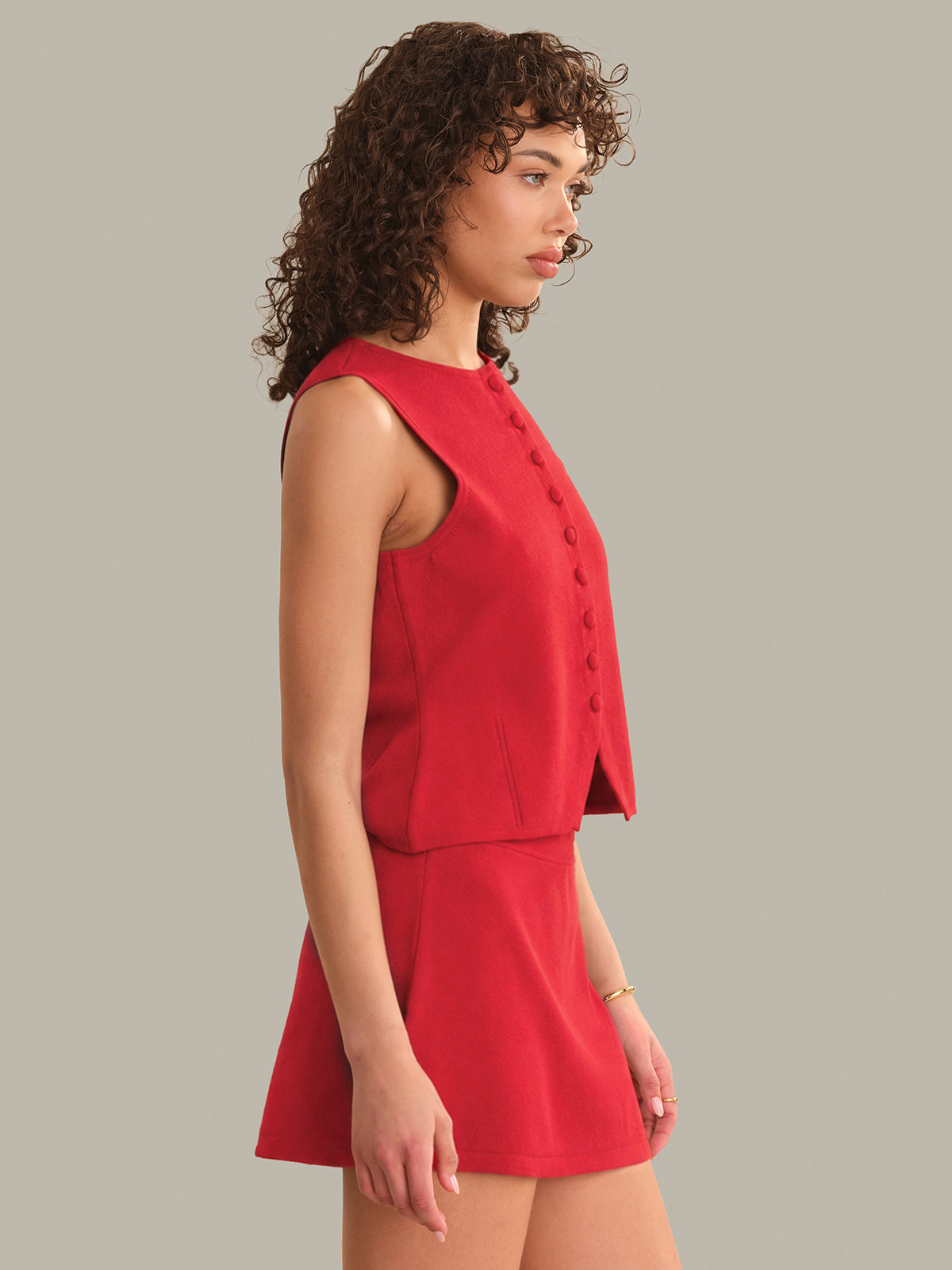Woman wearing a red sleeveless top and skirt against a gray background