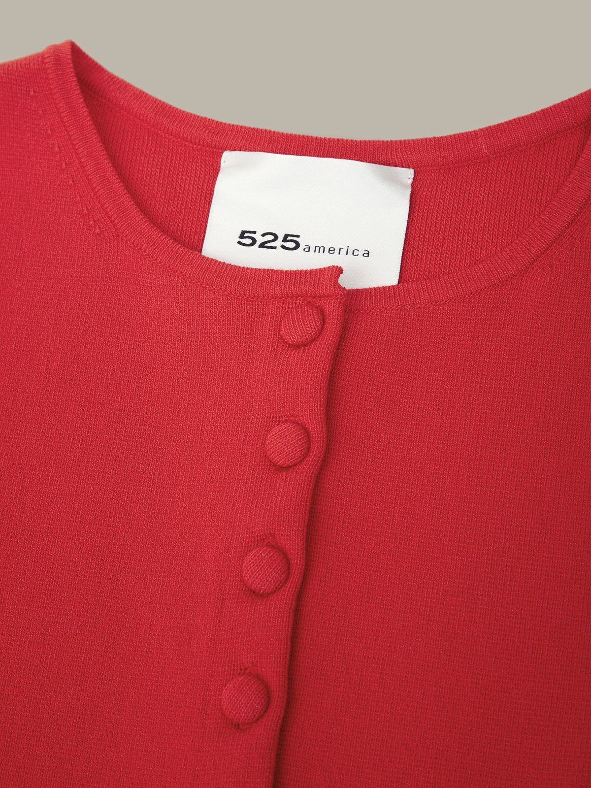 Red garment with a visible brand label on a neutral background