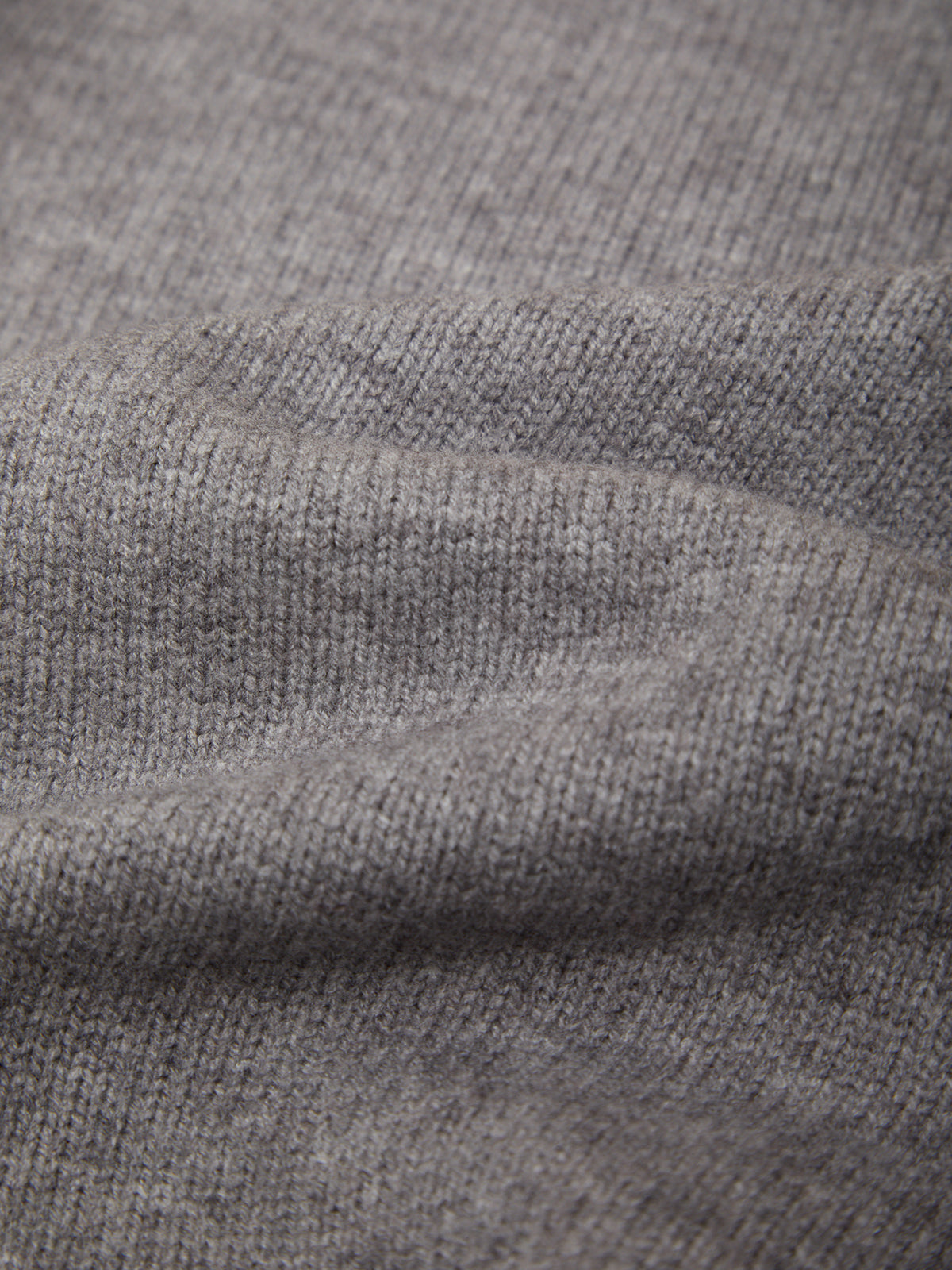 Close-up of a heather gray knit fabric texture with soft folds showing the ribbed weave detail.