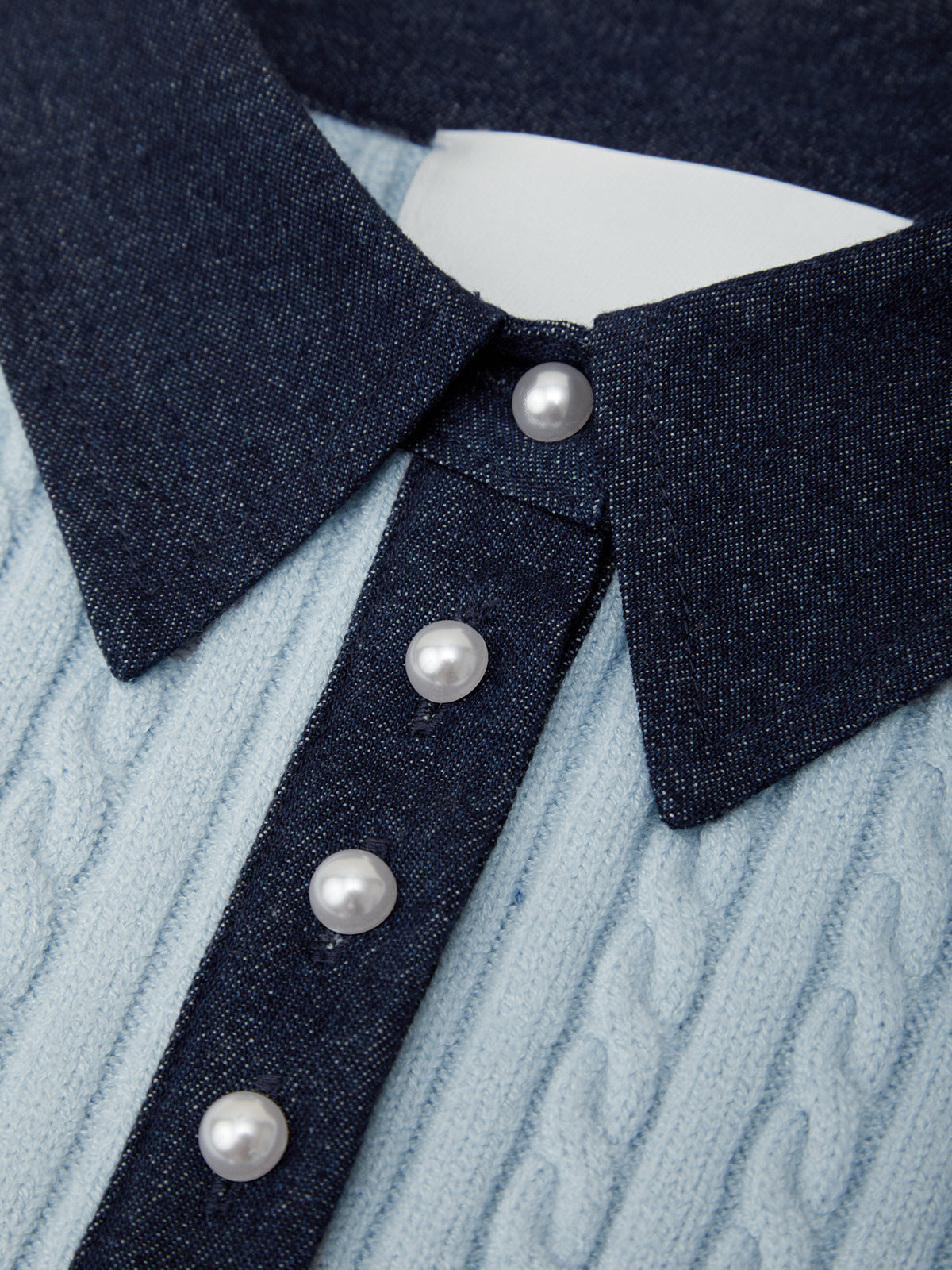 Close-up of a denim collar with pearl buttons on a textured fabric background