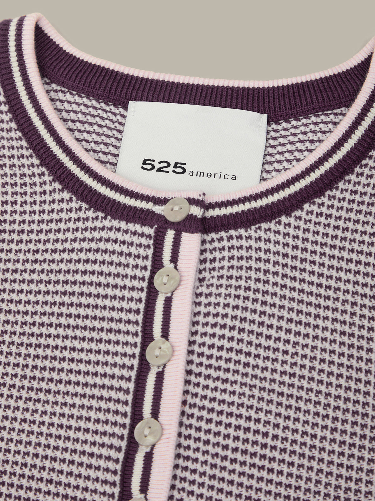 Close-up of a textured cardigan with a brand label on a gray background