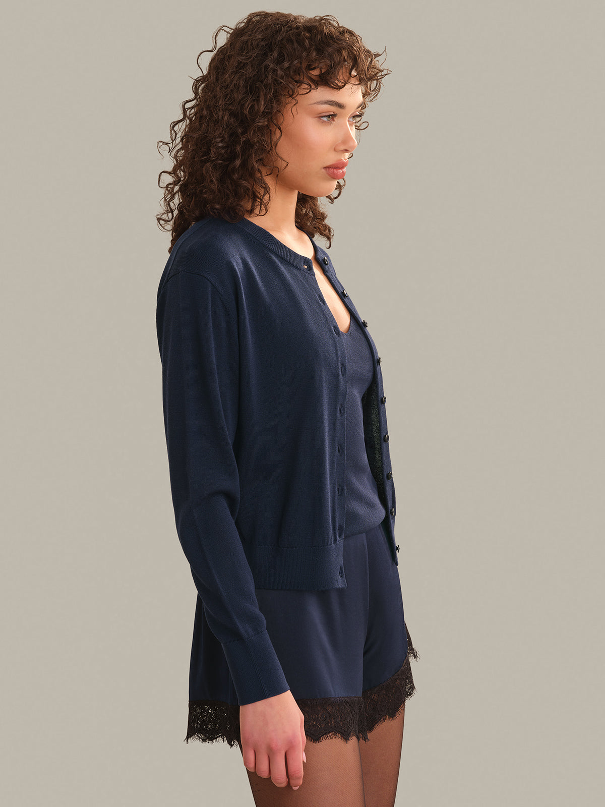 Woman wearing a navy blue cardigan on a plain background