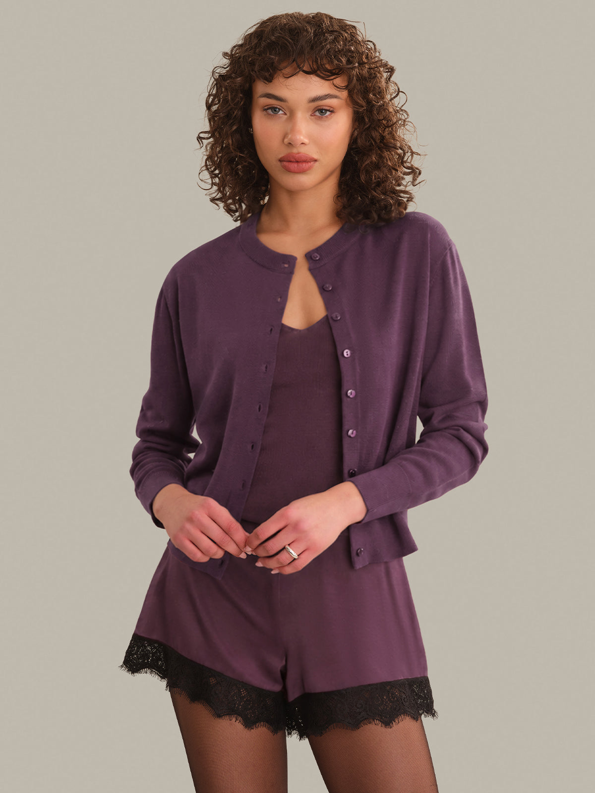 Woman wearing a purple cardigan with a plain background
