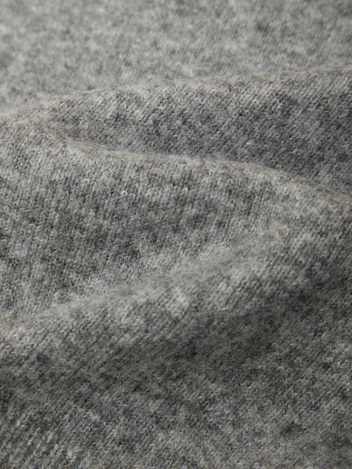 Close-up of a heather gray knit fabric with soft folds and a fine textured weave.
