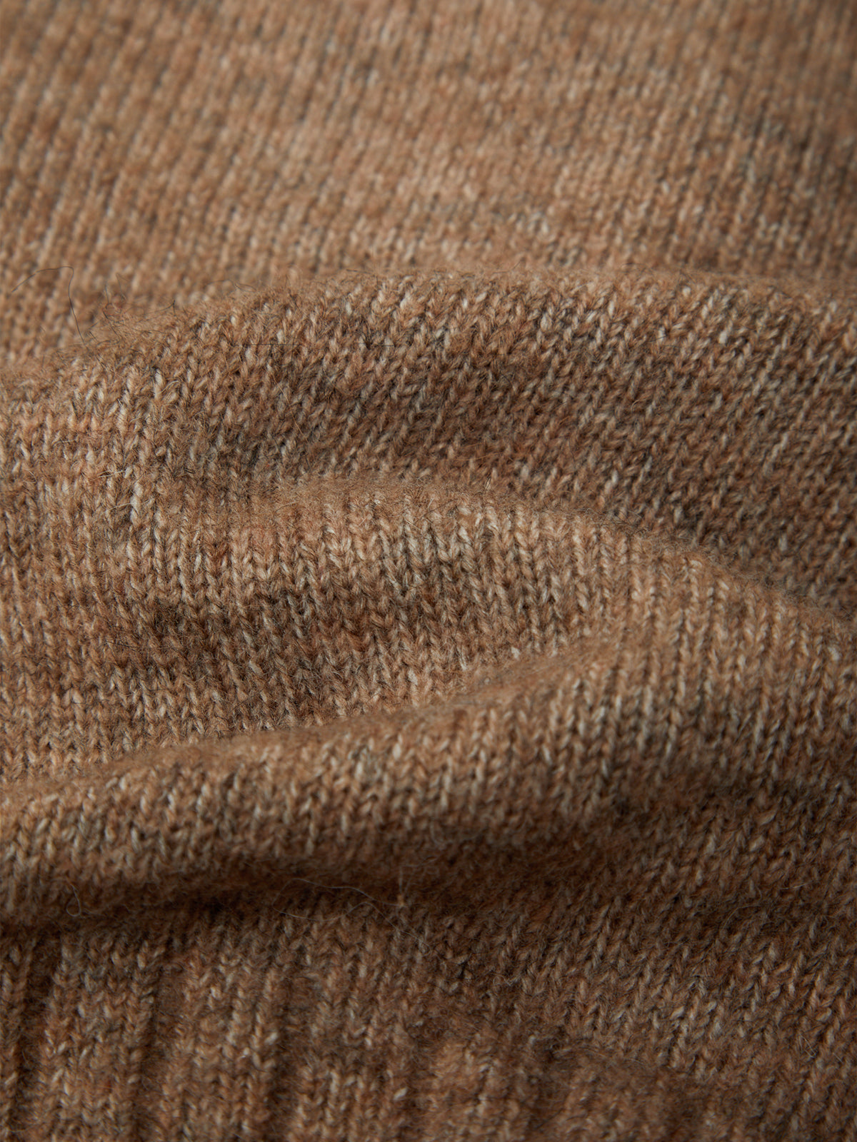 Close-up of a brown knit fabric texture with soft folds and ribbed detailing.