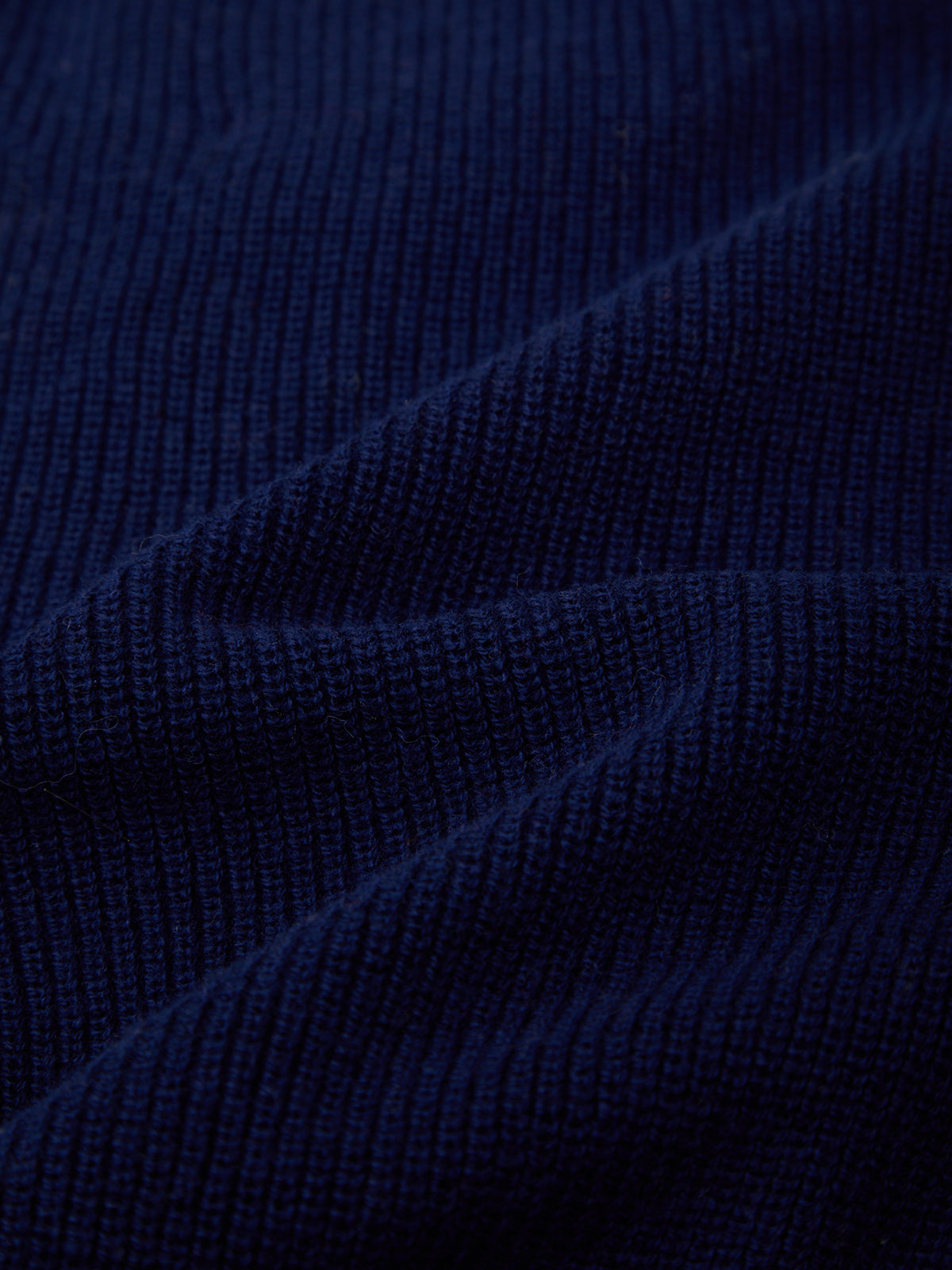 Close-up of dark navy blue ribbed knit fabric texture with soft folds.