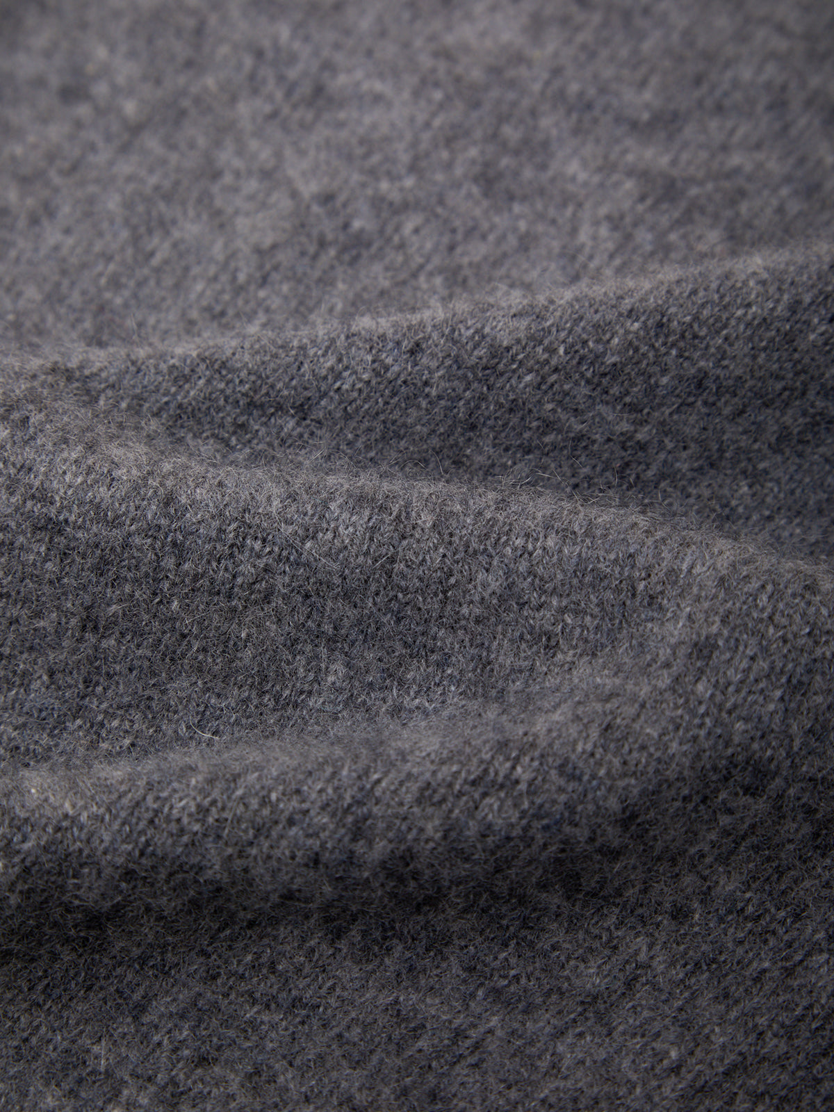 Close-up of a dark gray heathered knit fabric with soft folds and a fine textured weave.