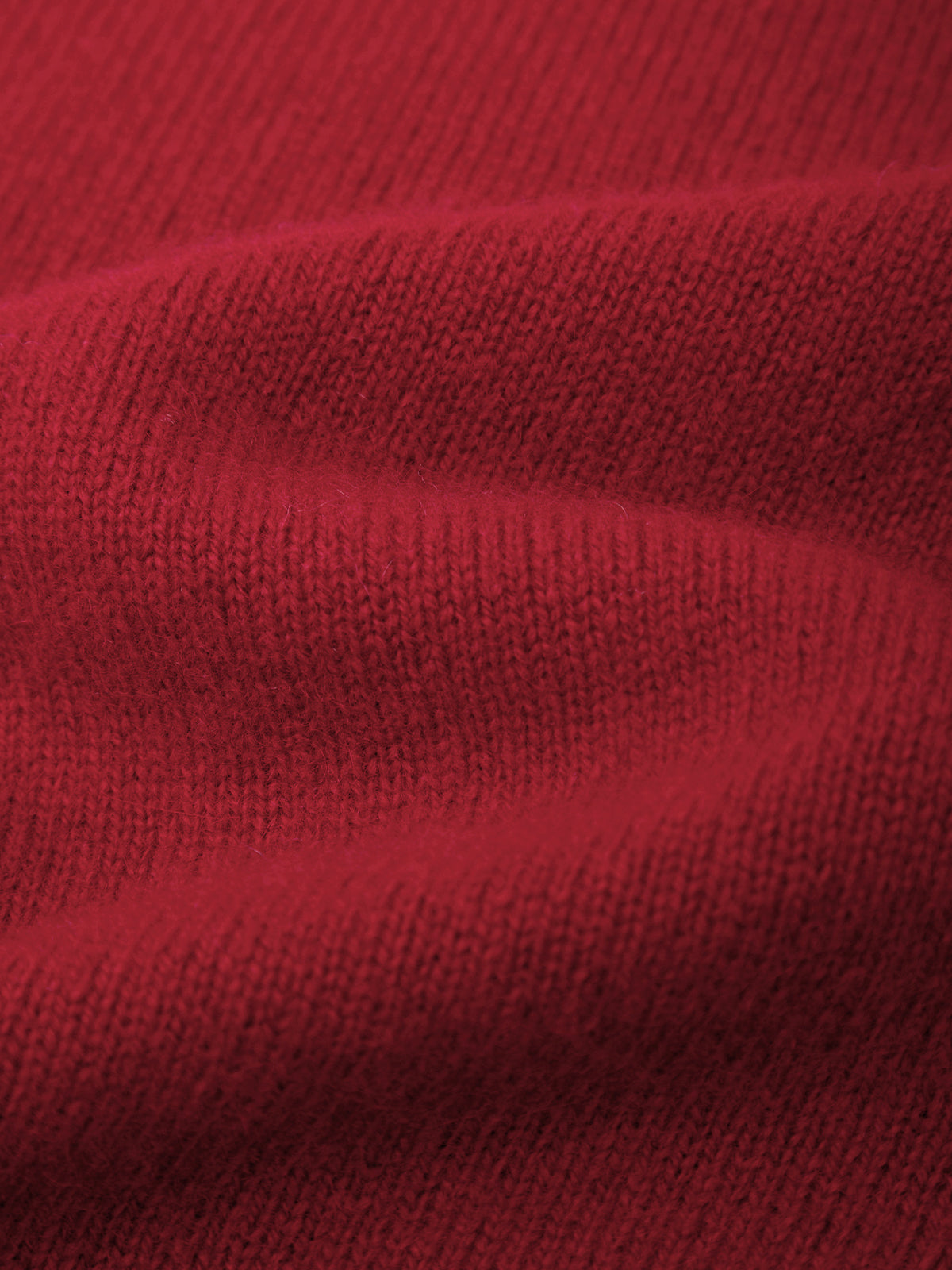 A close-up of a red knit fabric with visible ribbed texture and soft folds.