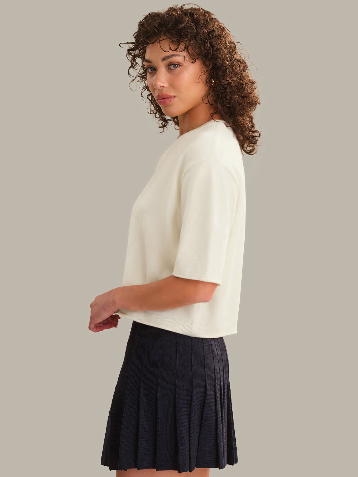 Woman wearing a white top and black skirt on a plain background