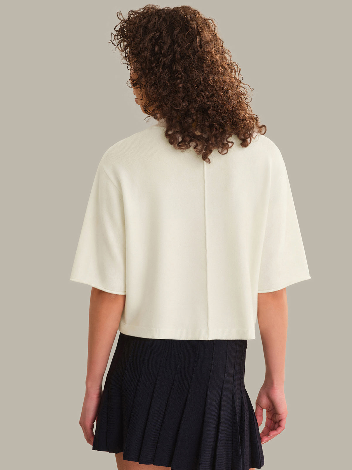 Person wearing a white top and black skirt on a plain background